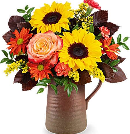Bouquet of sunflowers, roses, and orange daisies in a brown pitcher vase