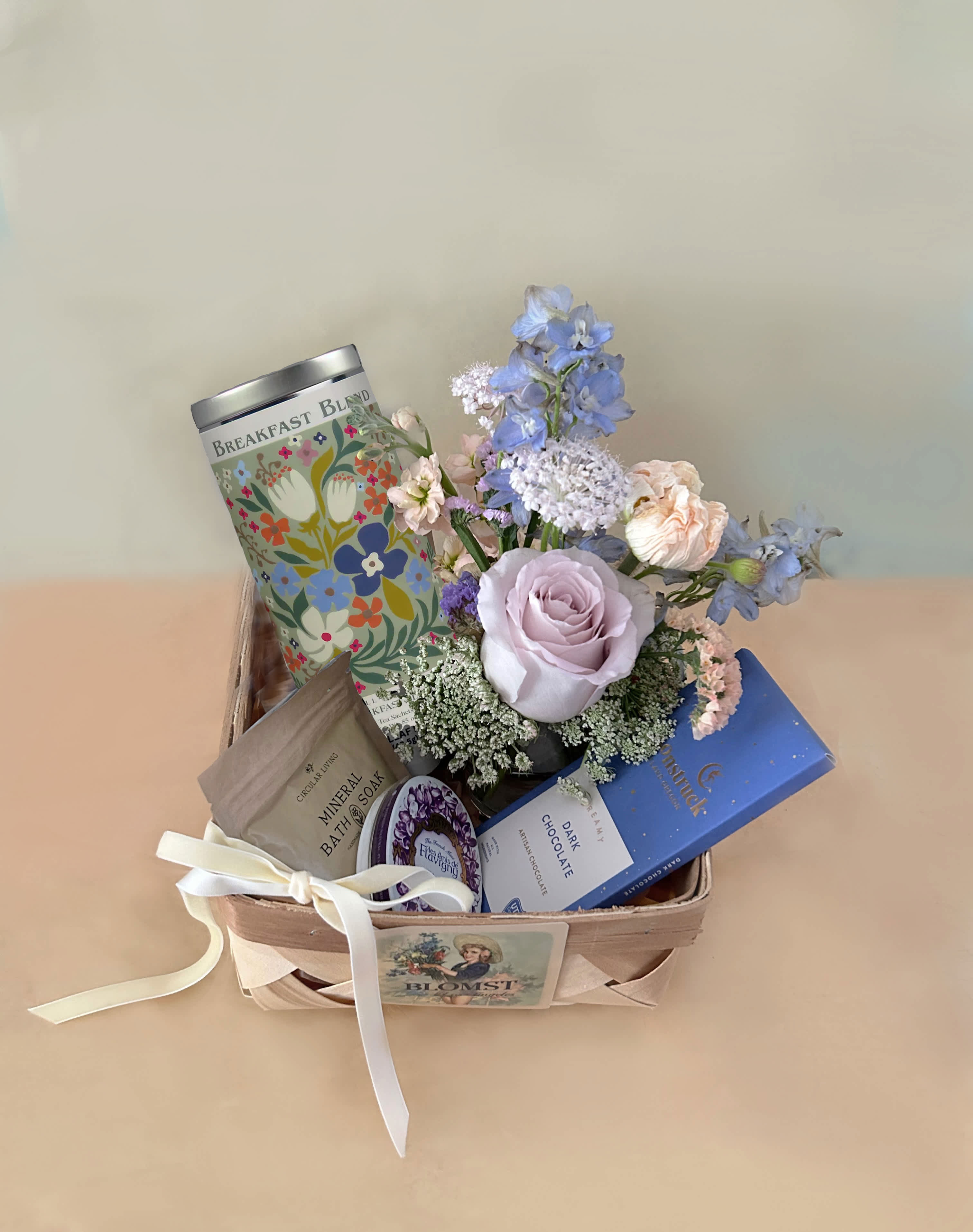 Gift basket with pastel flowers, tea, soap, and chocolate