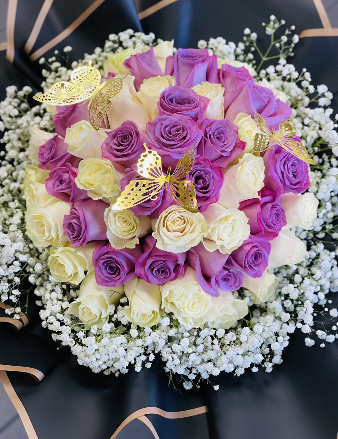 Bouquet of purple and cream roses with baby’s breath and gold butterfly picks