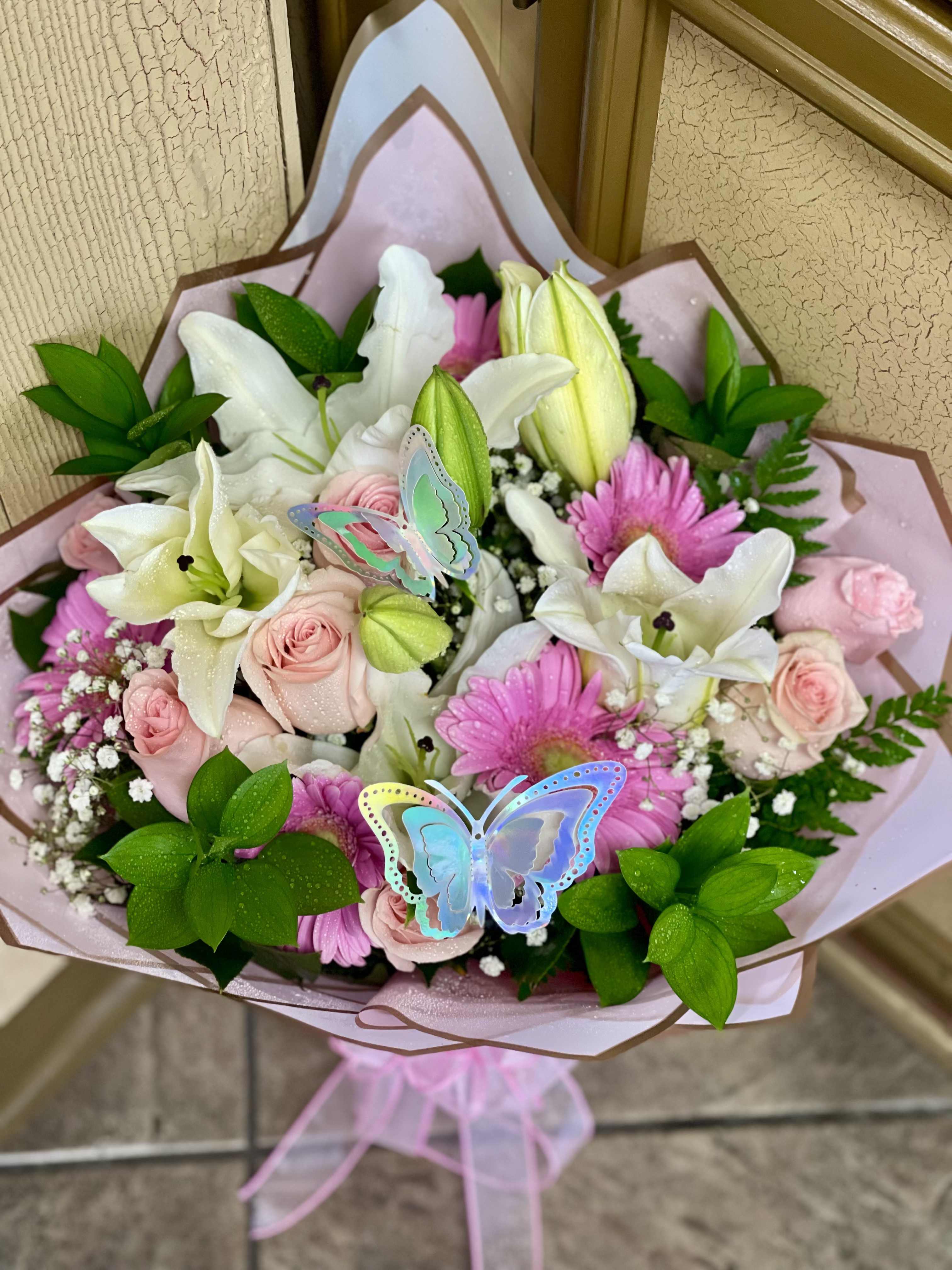 Bouquet of pink roses, white lilies, and pink daisies with butterfly picks