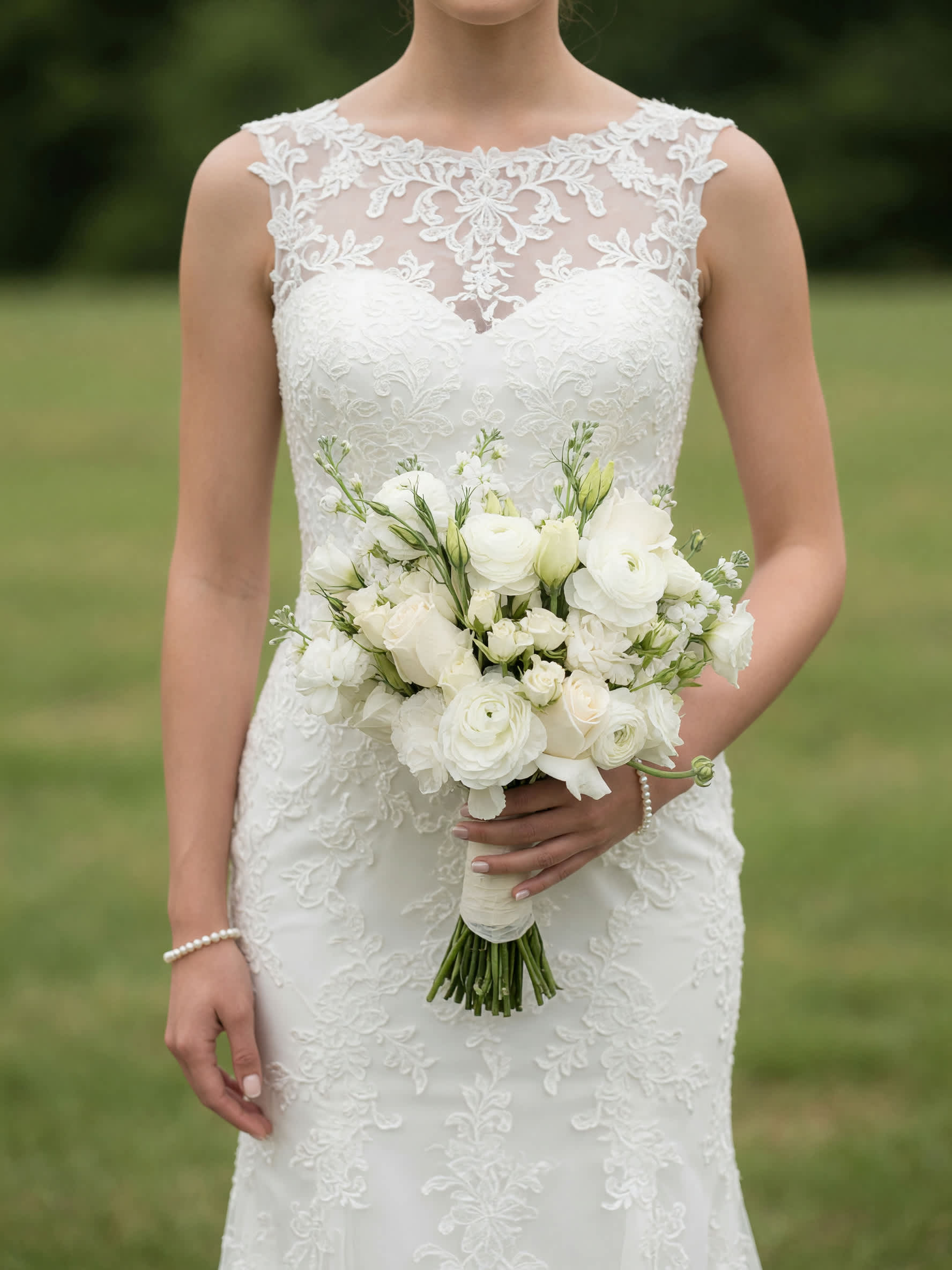 Bride holding a white bouquet with roses and ranunculus