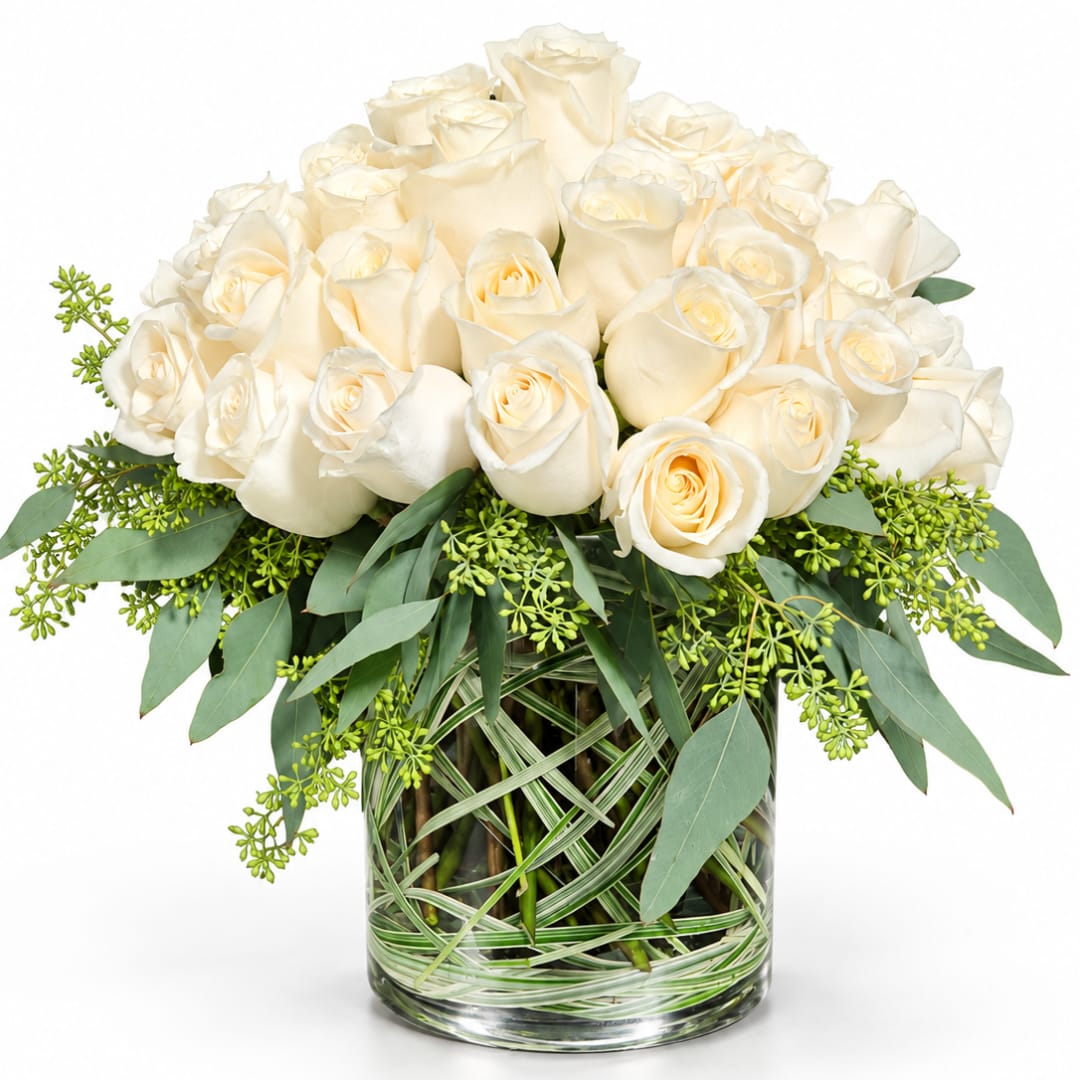 Bouquet of white roses in a glass vase with greenery