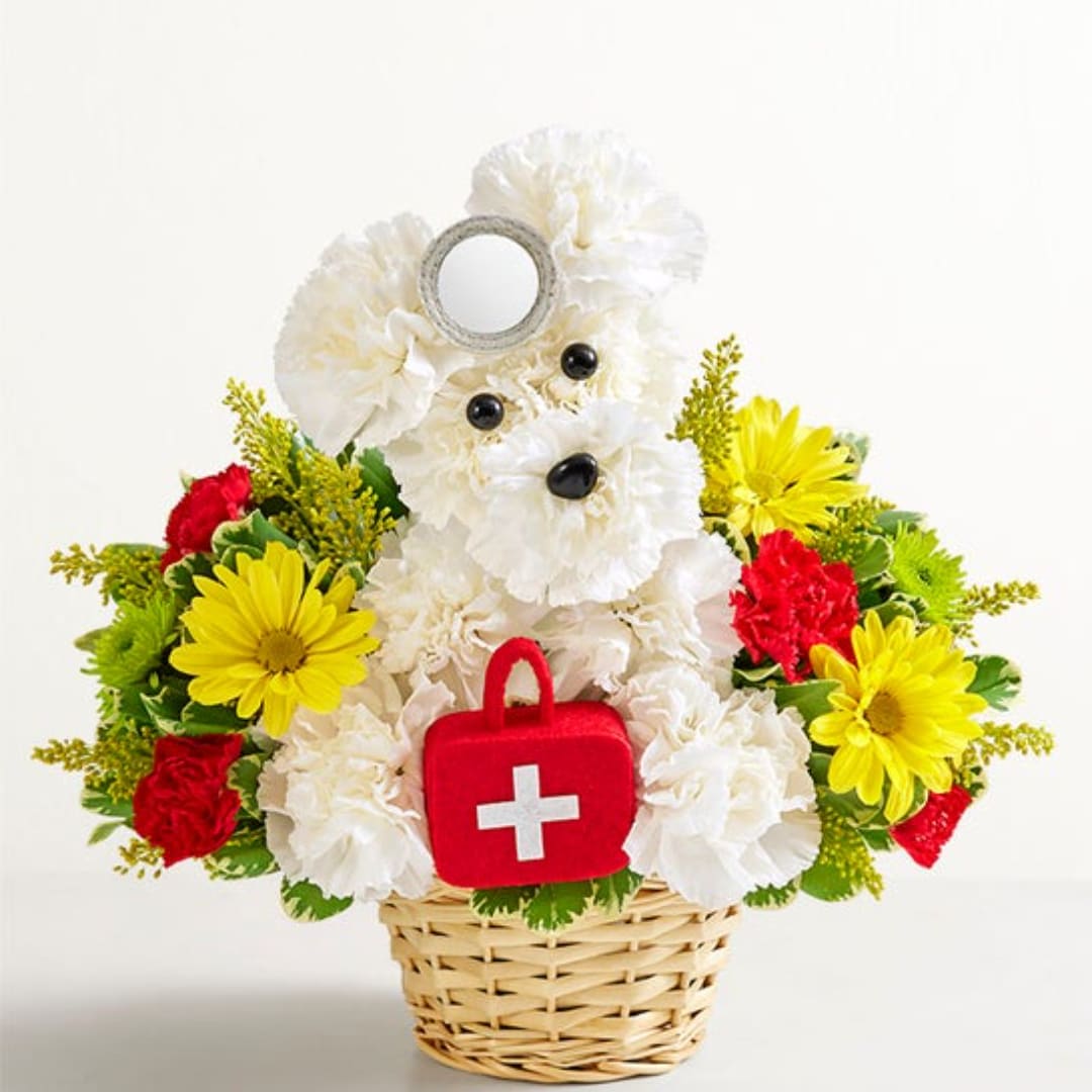 White teddy bear floral arrangement in a basket with a red first-aid bag