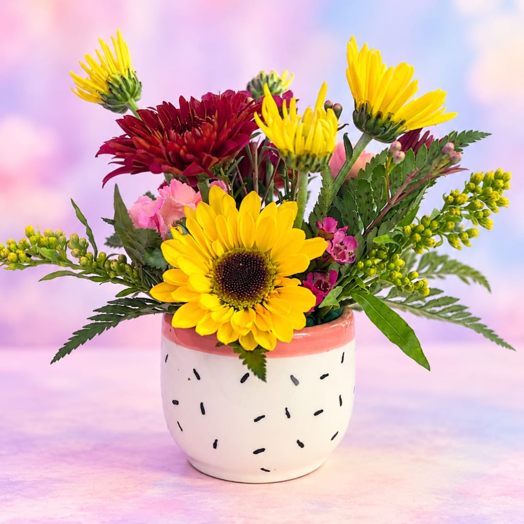 Bright mixed bouquet in a small ceramic pot with yellow and burgundy blooms