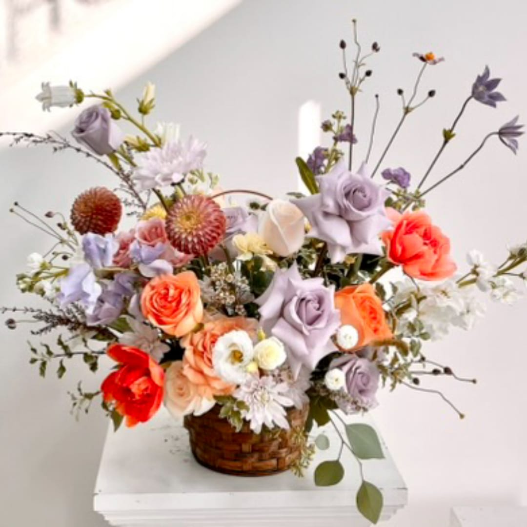 Mixed bouquet of roses and daisies in a woven basket