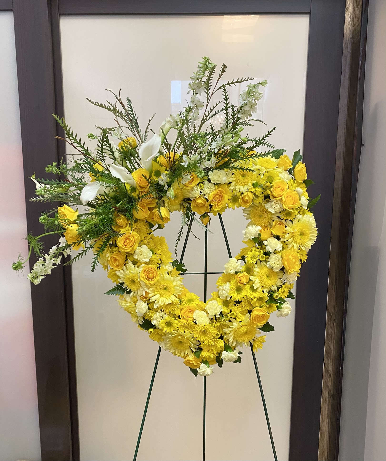 Yellow and white floral heart wreath on a stand