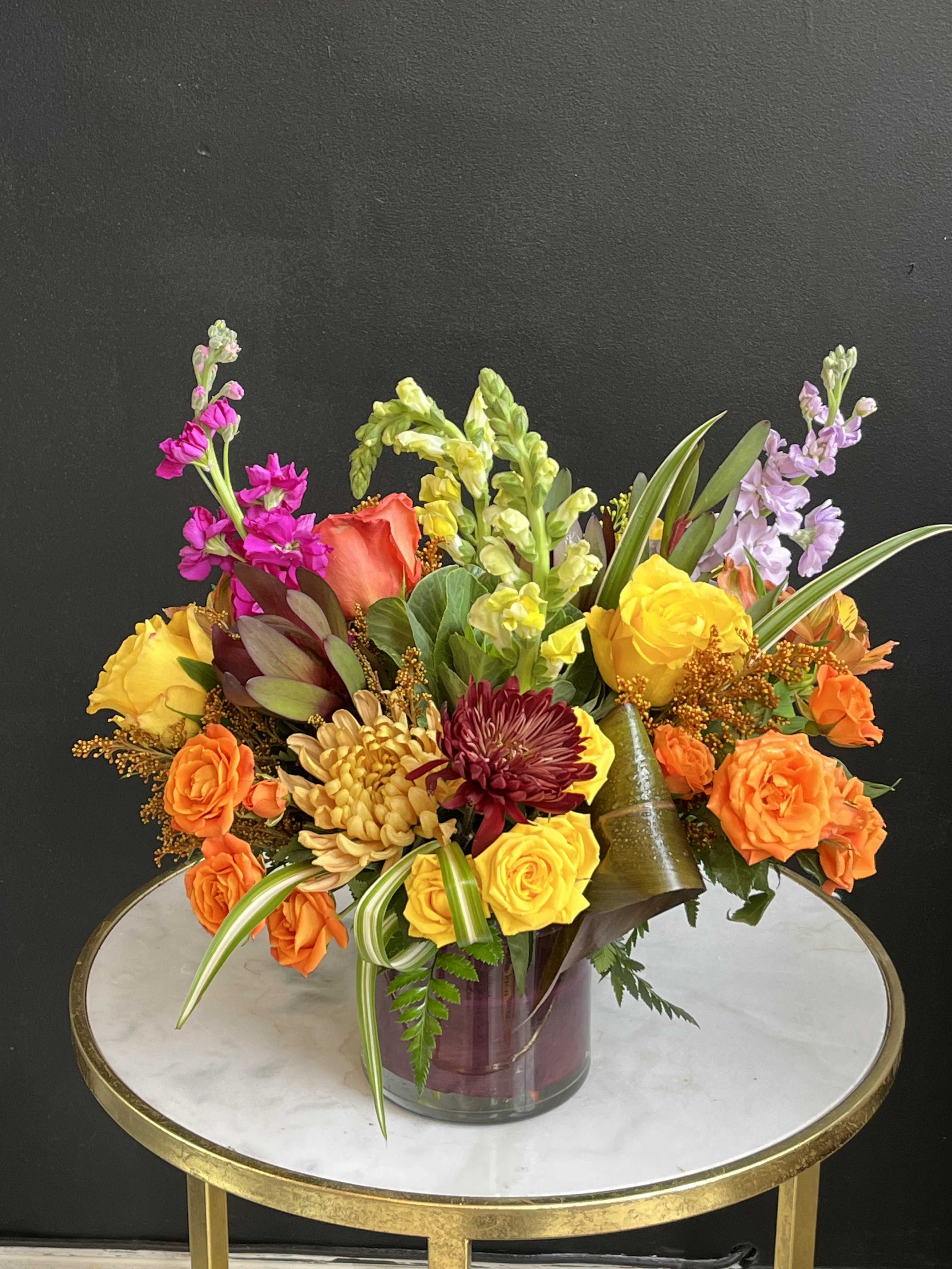 Colorful mixed bouquet in a glass vase with roses and snapdragons