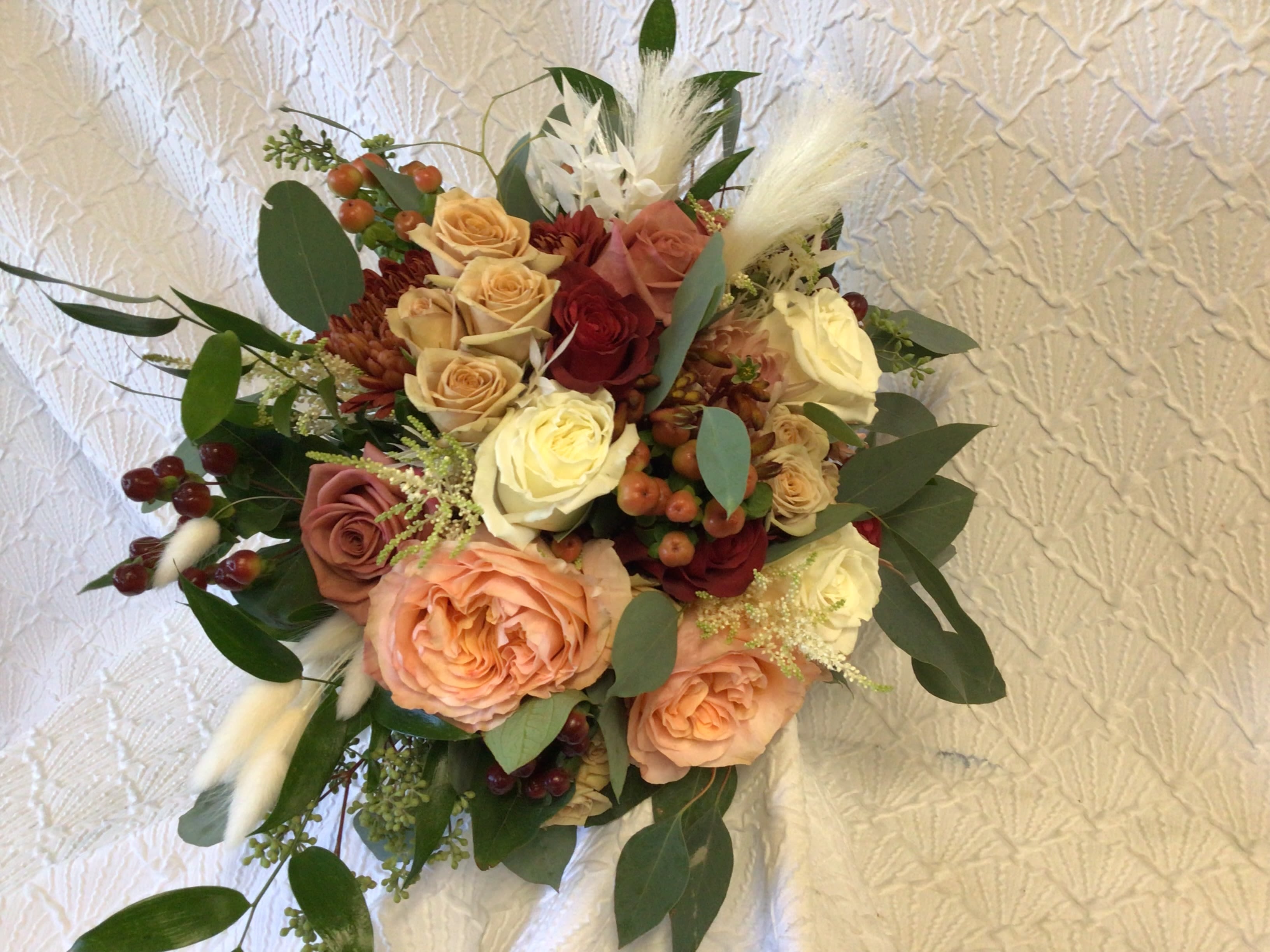 Bouquet of peach and cream roses with burgundy accents