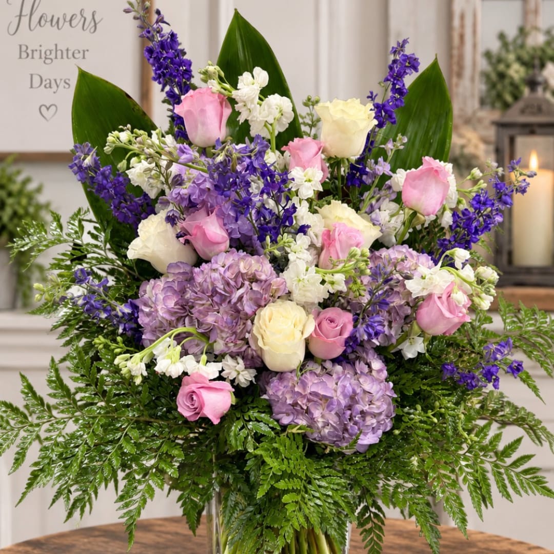 Pink and white roses with purple flowers in a glass vase