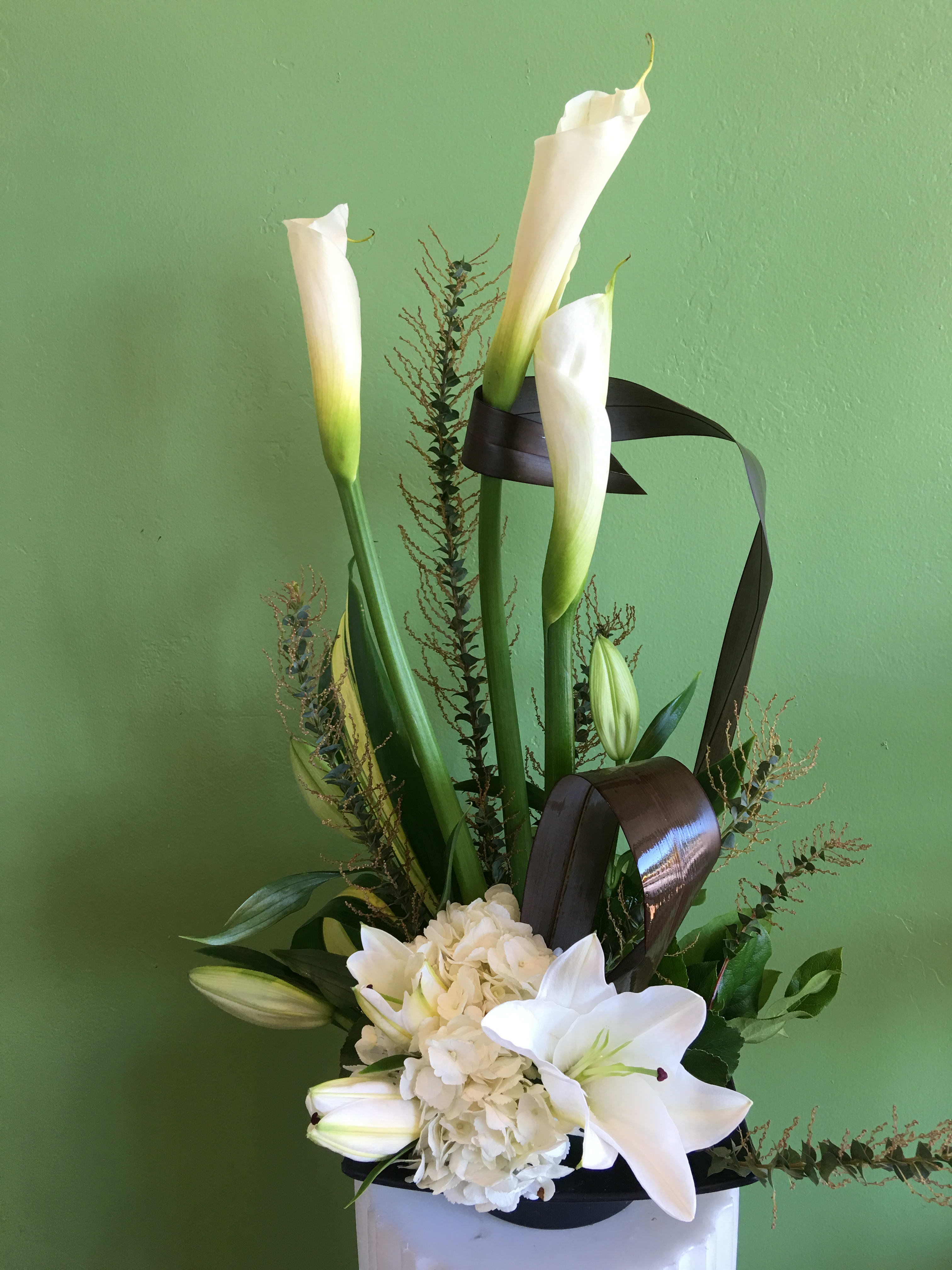 White calla lilies and lilies arranged with hydrangea in a vase