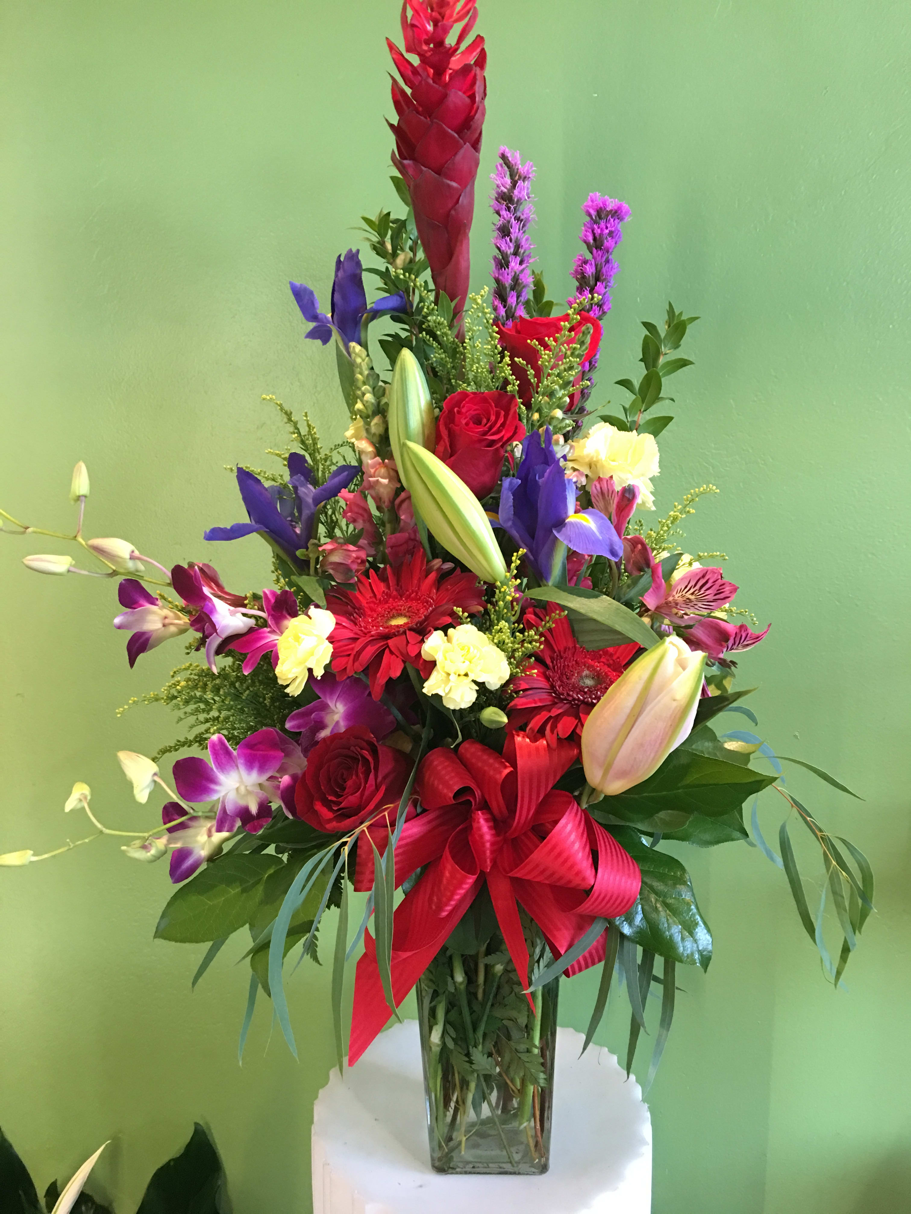 Tall mixed bouquet in a glass vase with red, purple, and yellow flowers
