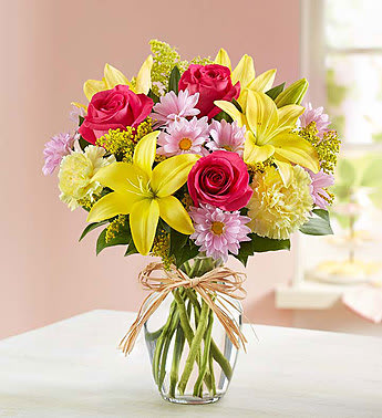 Bouquet of pink roses and yellow lilies in a glass vase
