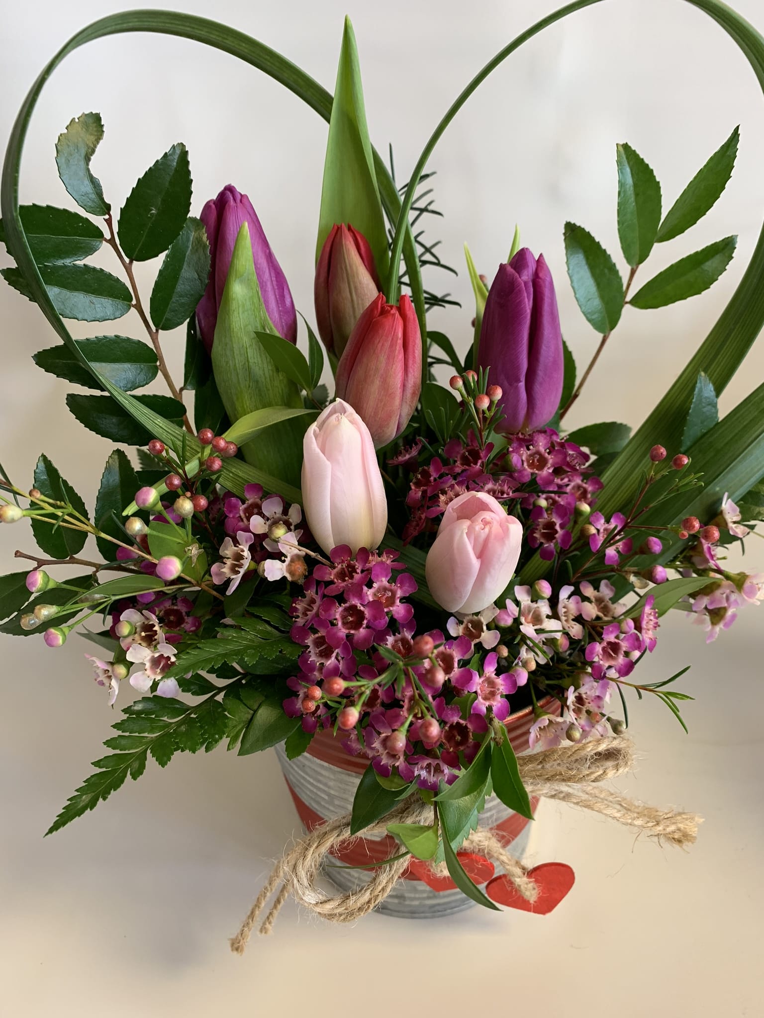 Pink and purple tulips in a striped vase with small blossoms