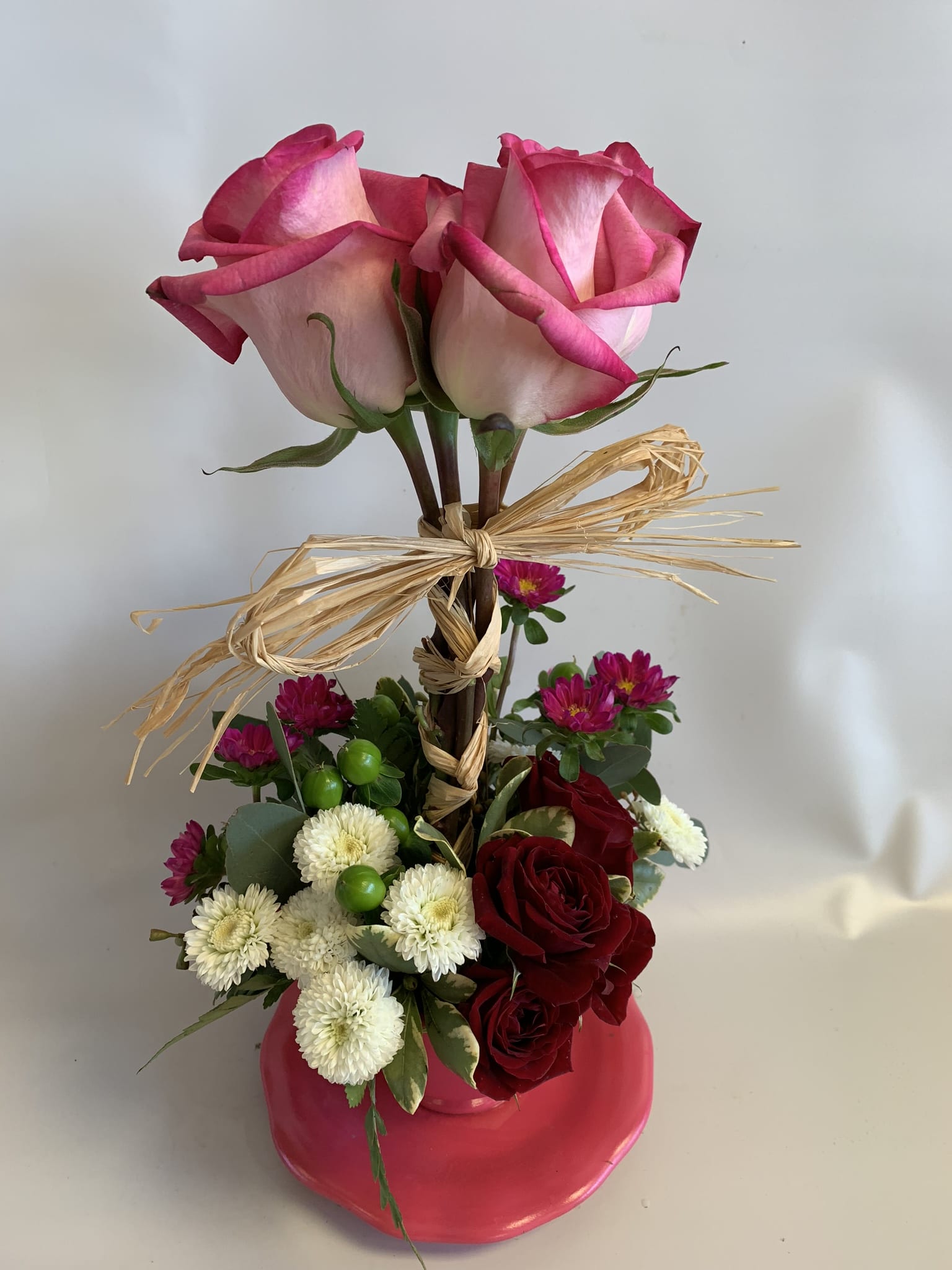 Pink roses in a vase with red and white flowers