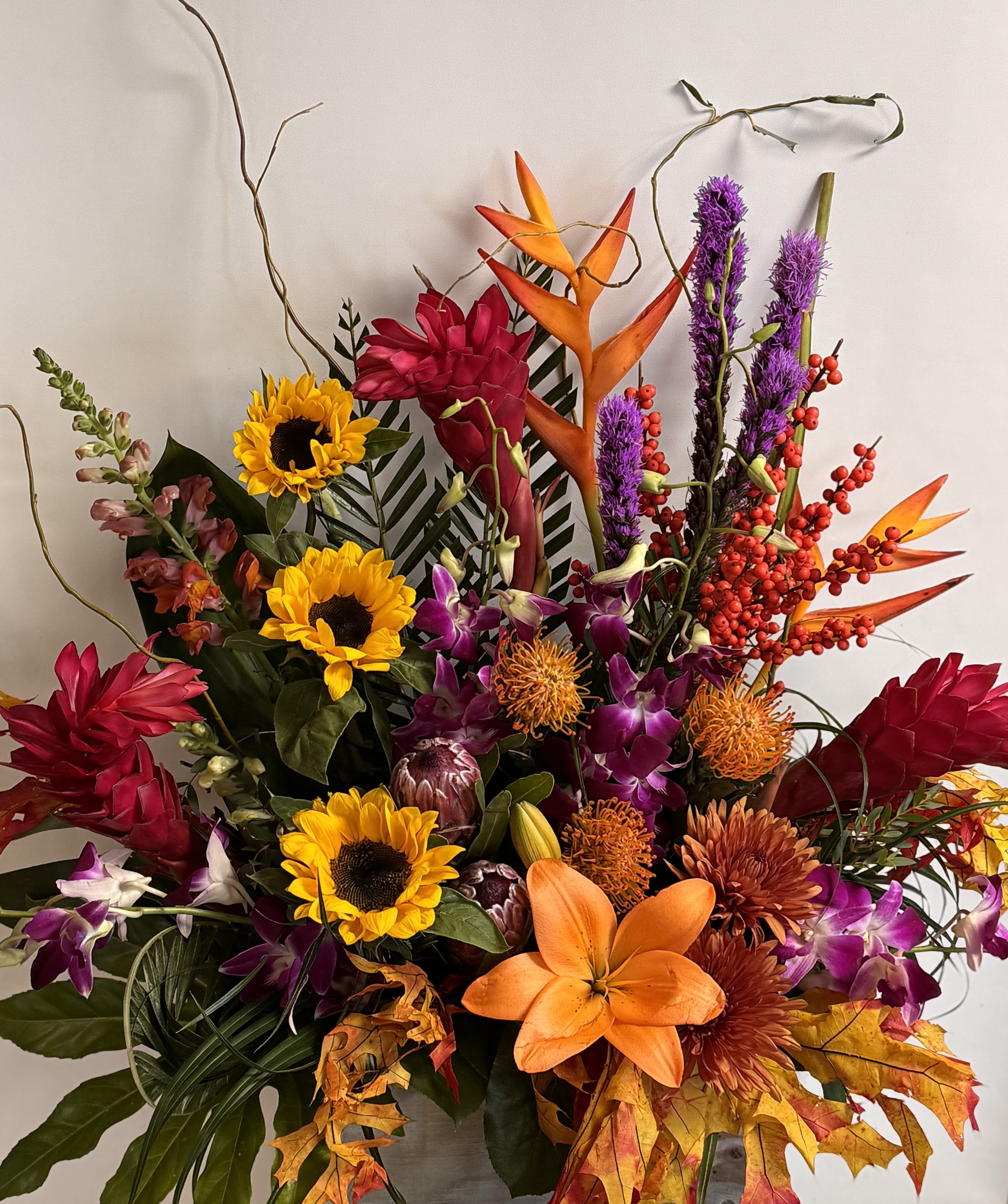 Colorful tropical bouquet with sunflowers, lilies, orchids, and orange bird-of-paradise