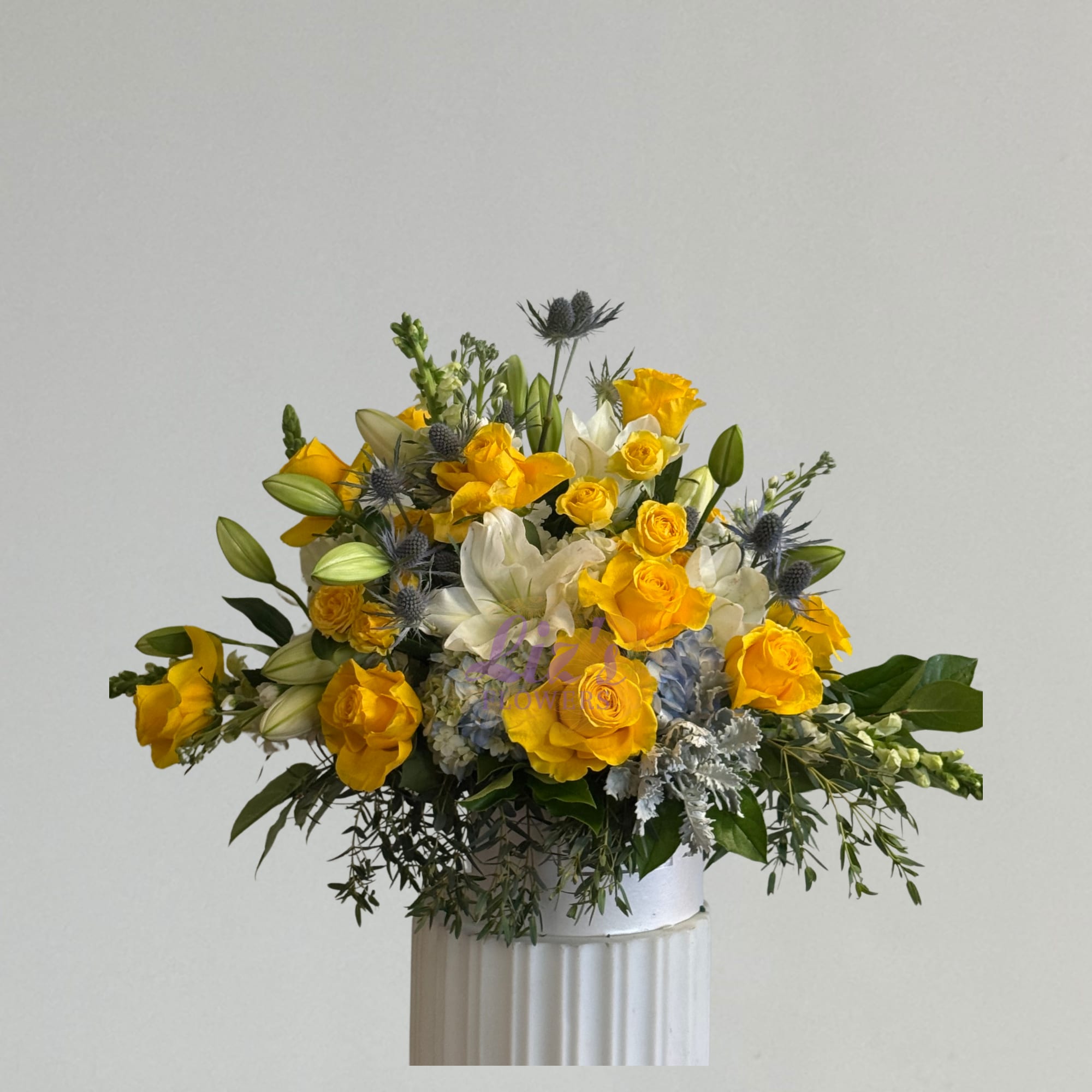 Yellow and white floral arrangement in a white vase