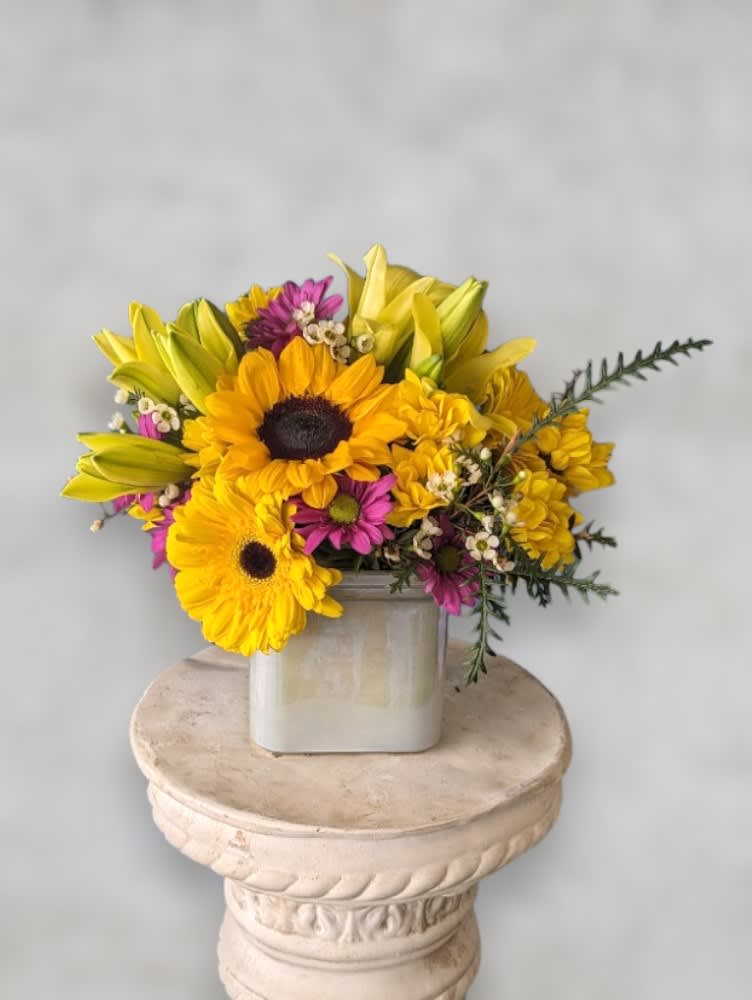 Sunny Days by Art &amp; Flowers - Introducing our sunshine in a cube! This radiant yellow flower arrangement, nestled in a sleek glass cube, is the perfect burst of joy for any space. With cheerful blooms that dance in the light, it's an instant mood lifter for your home or office. Brighten up your day with this effortlessly chic and vibrant arrangement