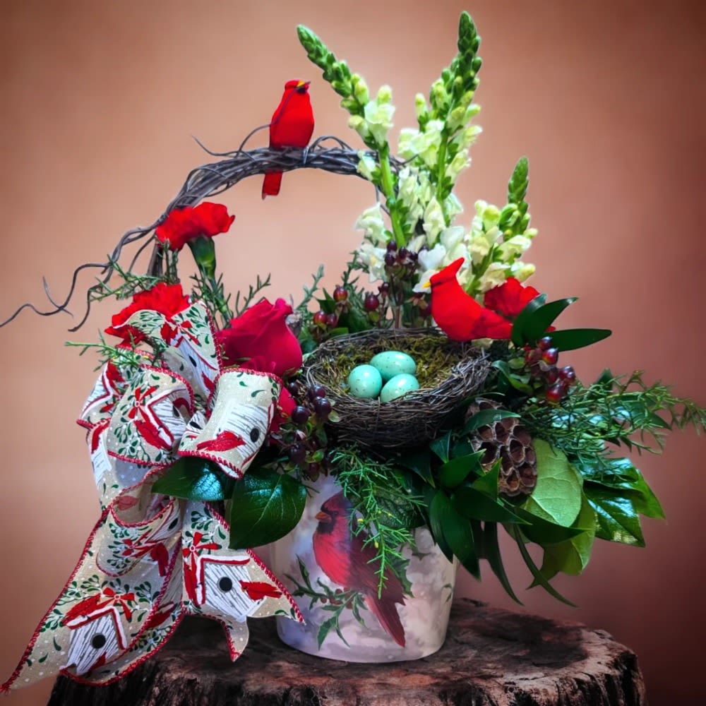 Festive floral arrangement with red flowers, white spikes, and a bird nest centerpiece