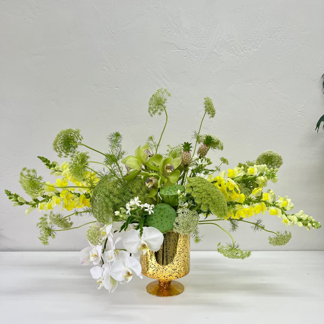 Green and white floral arrangement in a gold speckled vase
