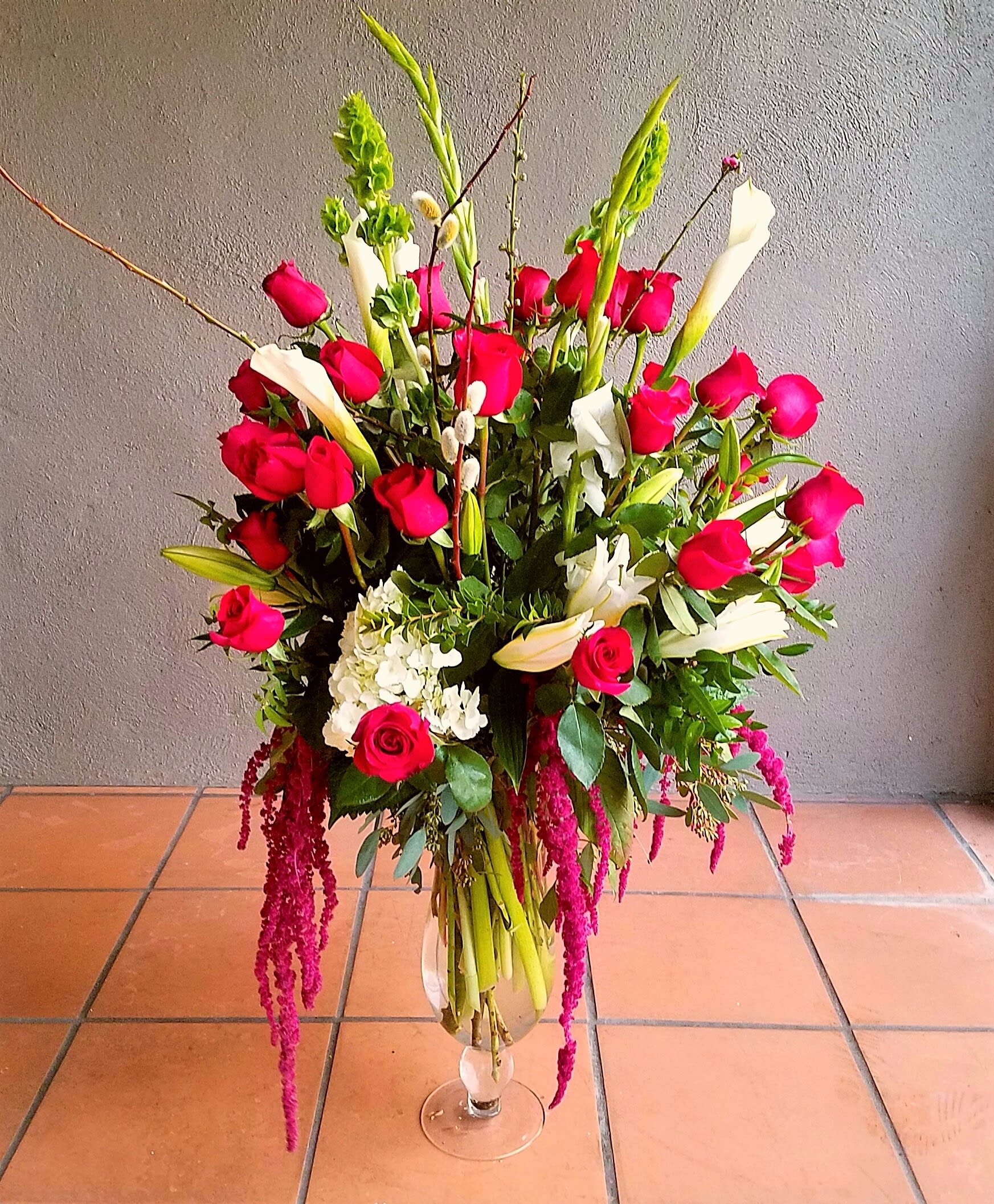 Tall bouquet of red roses, white calla lilies, and lilies in a glass vase