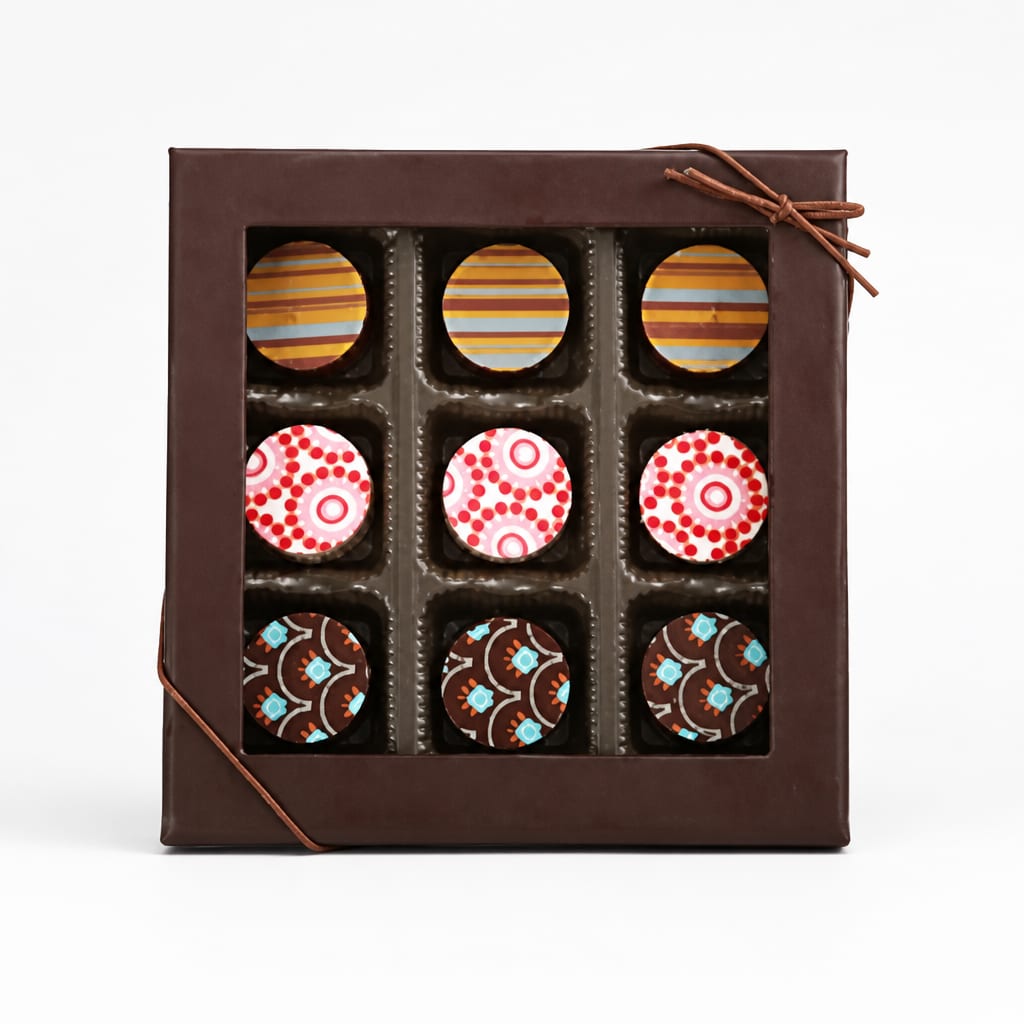 Box of assorted chocolates with patterned tops in a brown gift box
