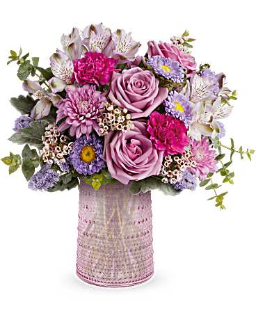Garden Melody Bouquet - Make Mother's Day special with Teleflora's Sparkling Joy Carafe, a pink glass keepsake with elegant beaded details. Designed to meet FDA tableware standards for safe serving and storage, it perfectly complements a delicate bouquet of lavender and pink blooms, creating a timeless and graceful gift. Teleflora's Garden Melody Bouquet showcases lavender roses, lavender alstroemeria, fuchsia carnations, lavender Matsumoto asters, lavender cushion spray chrysanthemums, lavender sinuata statice, pink waxflower, dusty miller, and spiral eucalyptus. Arranged in a pink glass carafe with beaded details, it's a timeless gift for Mom. Approximately 16 1/2" W x 15 1/2" H
