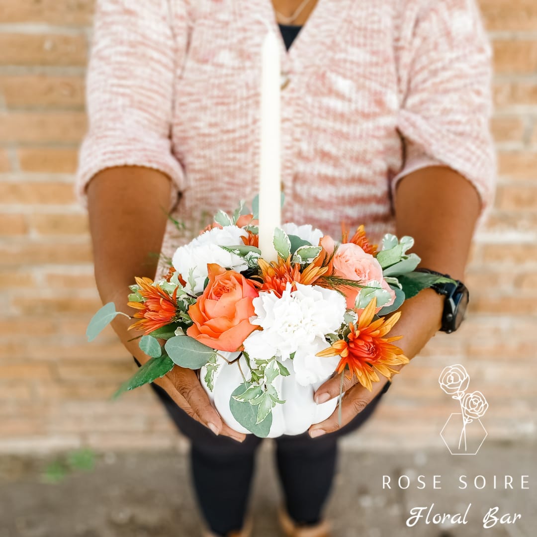 White pumpkin centerpiece with orange and white flowers and a candle