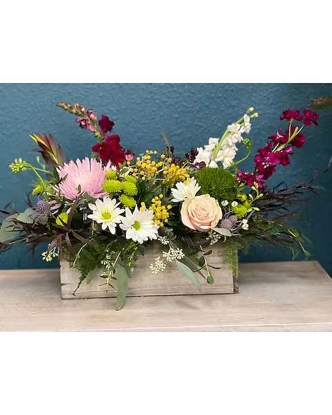 Mixed floral arrangement in a wooden box with pink, white, and burgundy blooms
