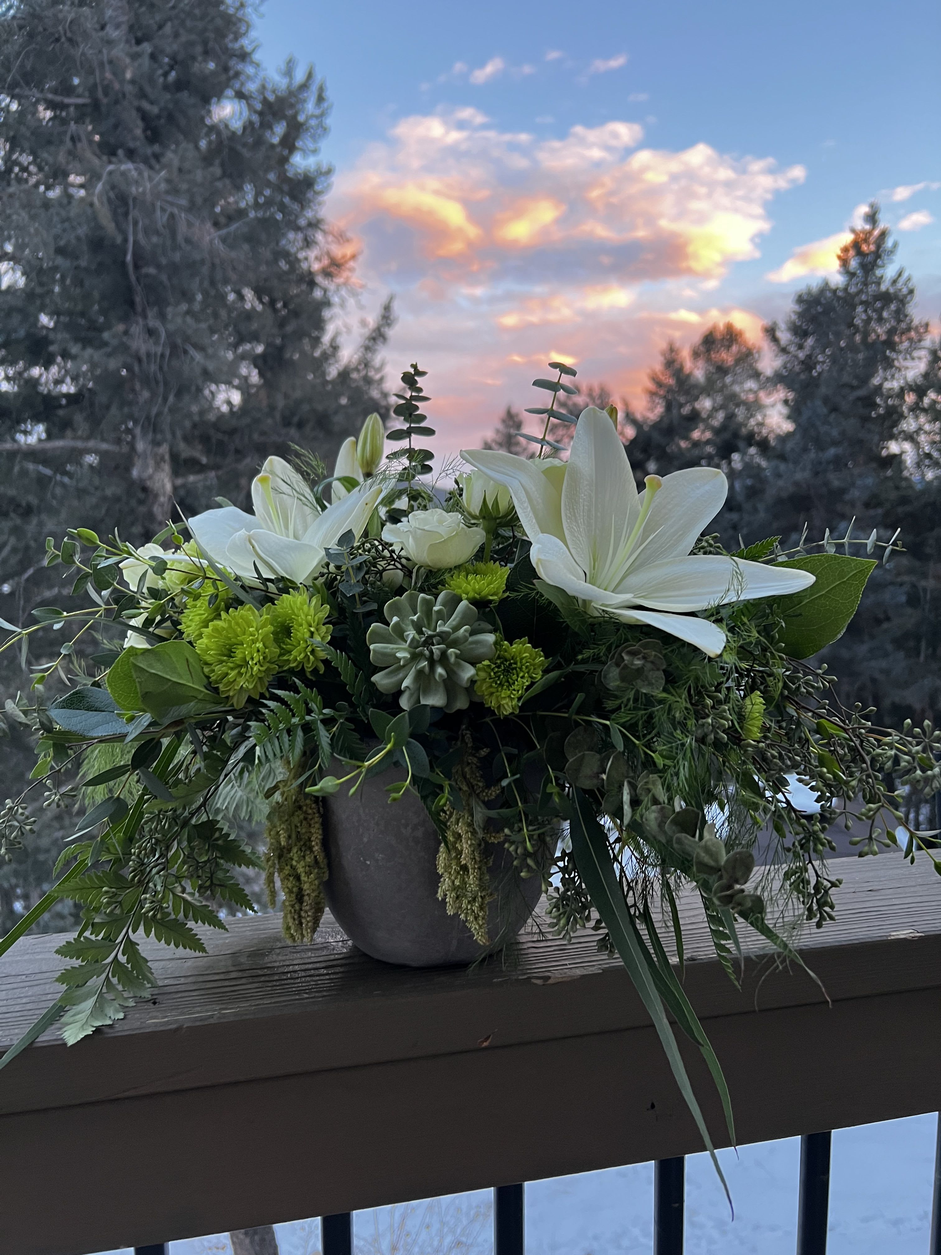 White lilies and green blooms in a gray vase