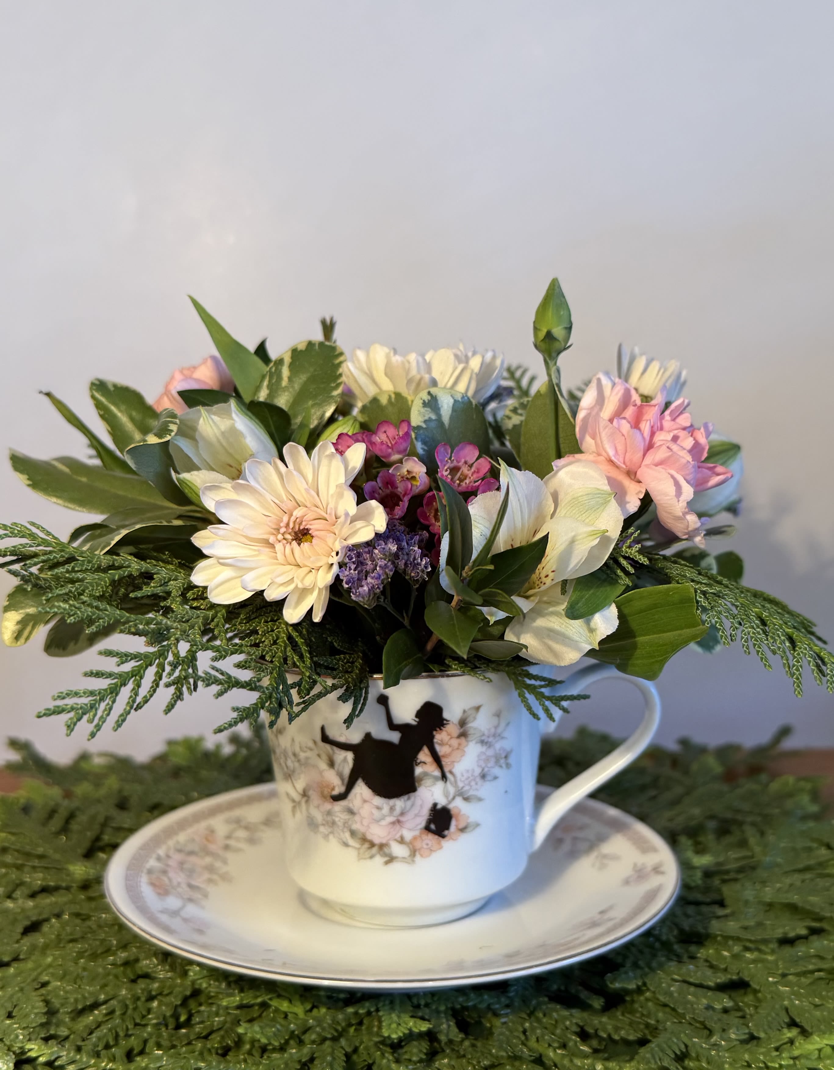 Pastel flower arrangement in a teacup on a saucer