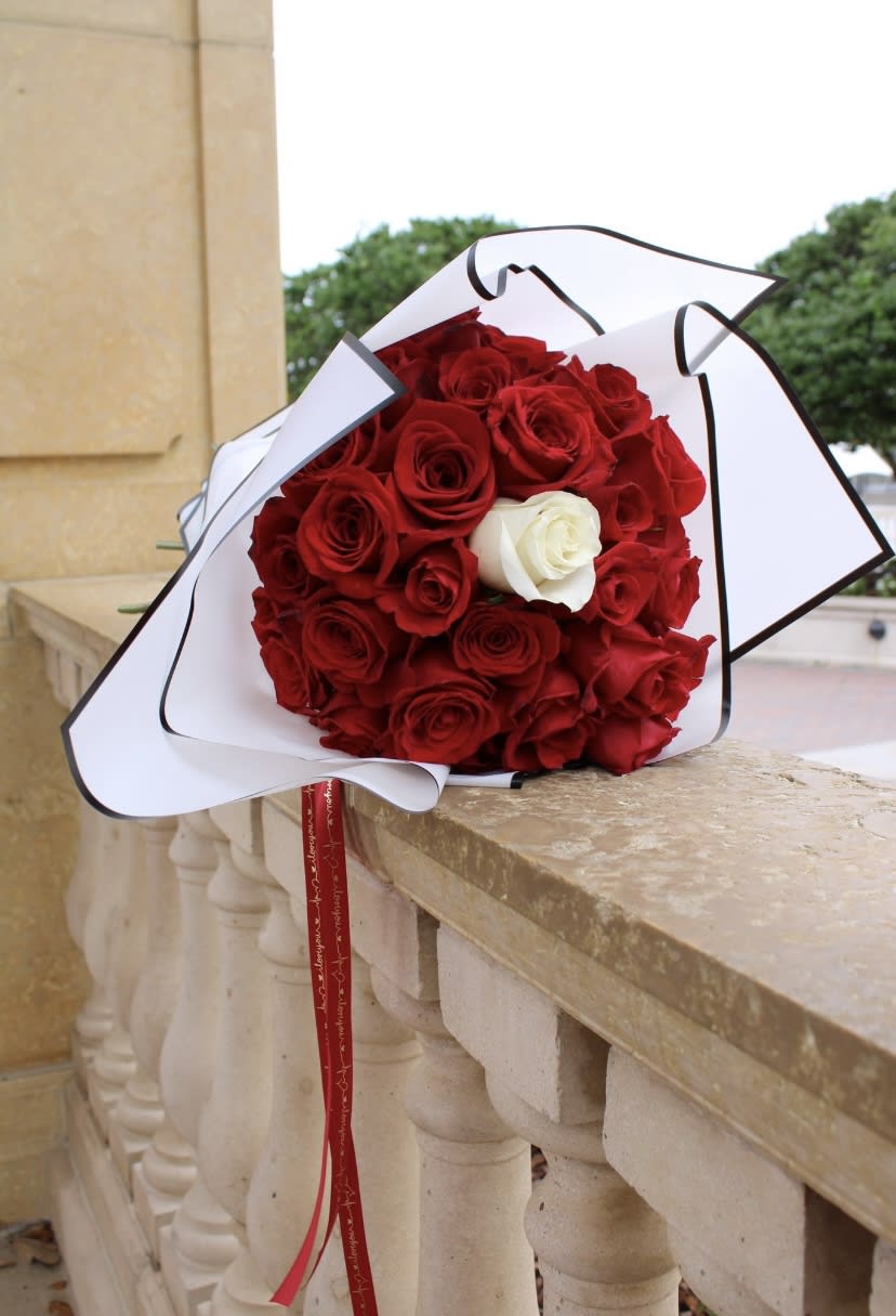 Bouquet of red roses with one white rose in white wrapping