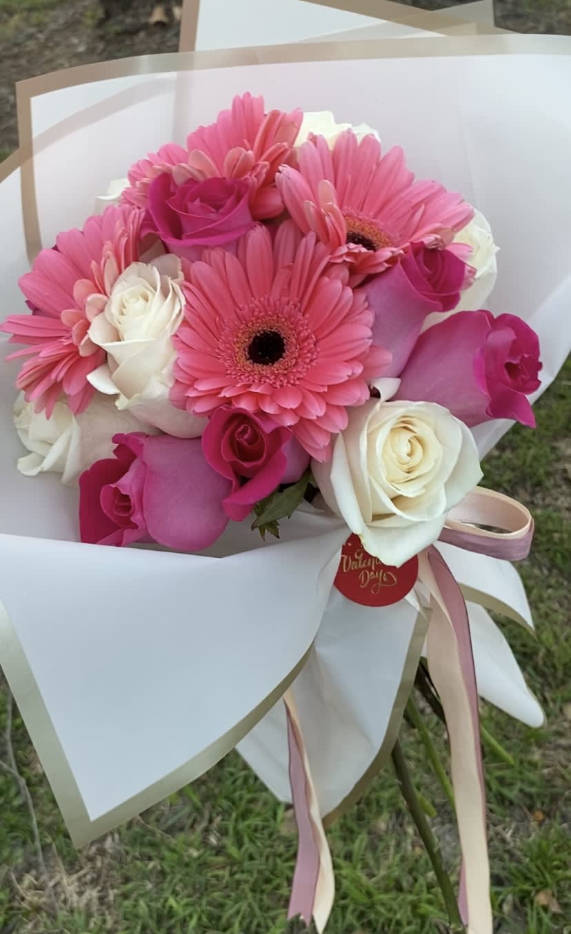 Pink gerbera daisies and roses wrapped in white paper