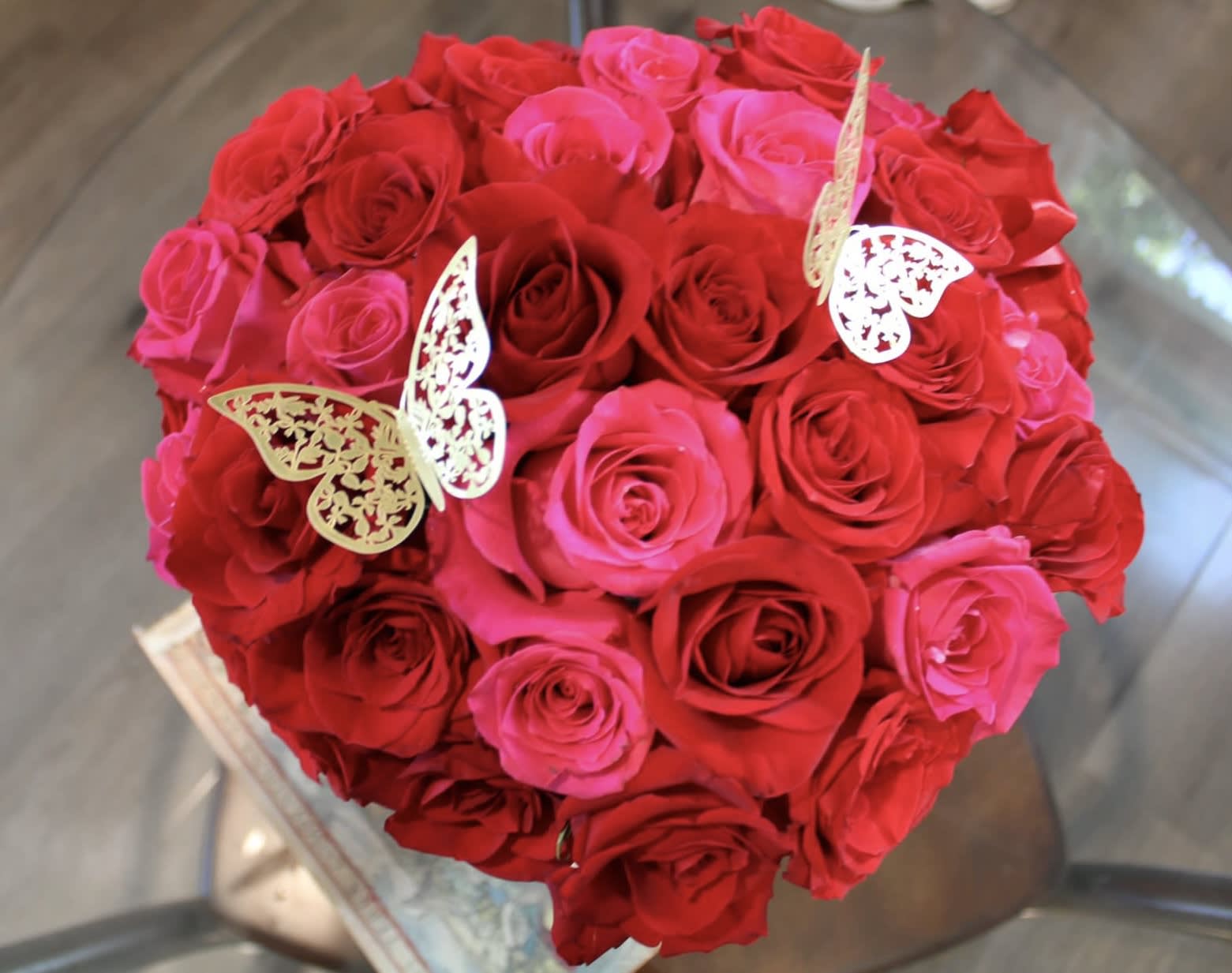 Heart-shaped bouquet of red and pink roses with butterfly picks