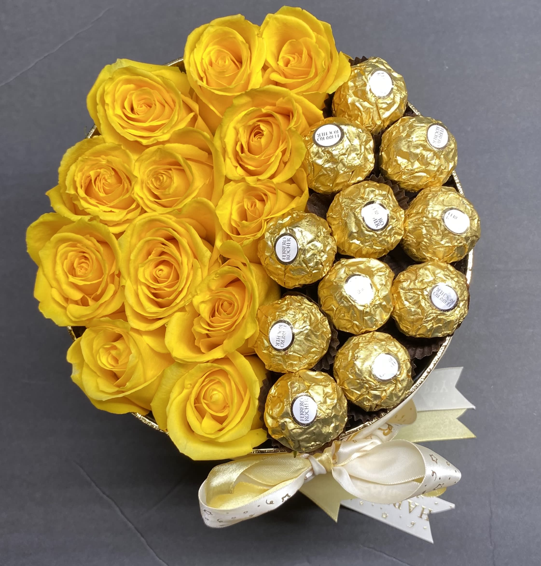 Yellow roses arranged with gold-wrapped chocolates in a round bouquet
