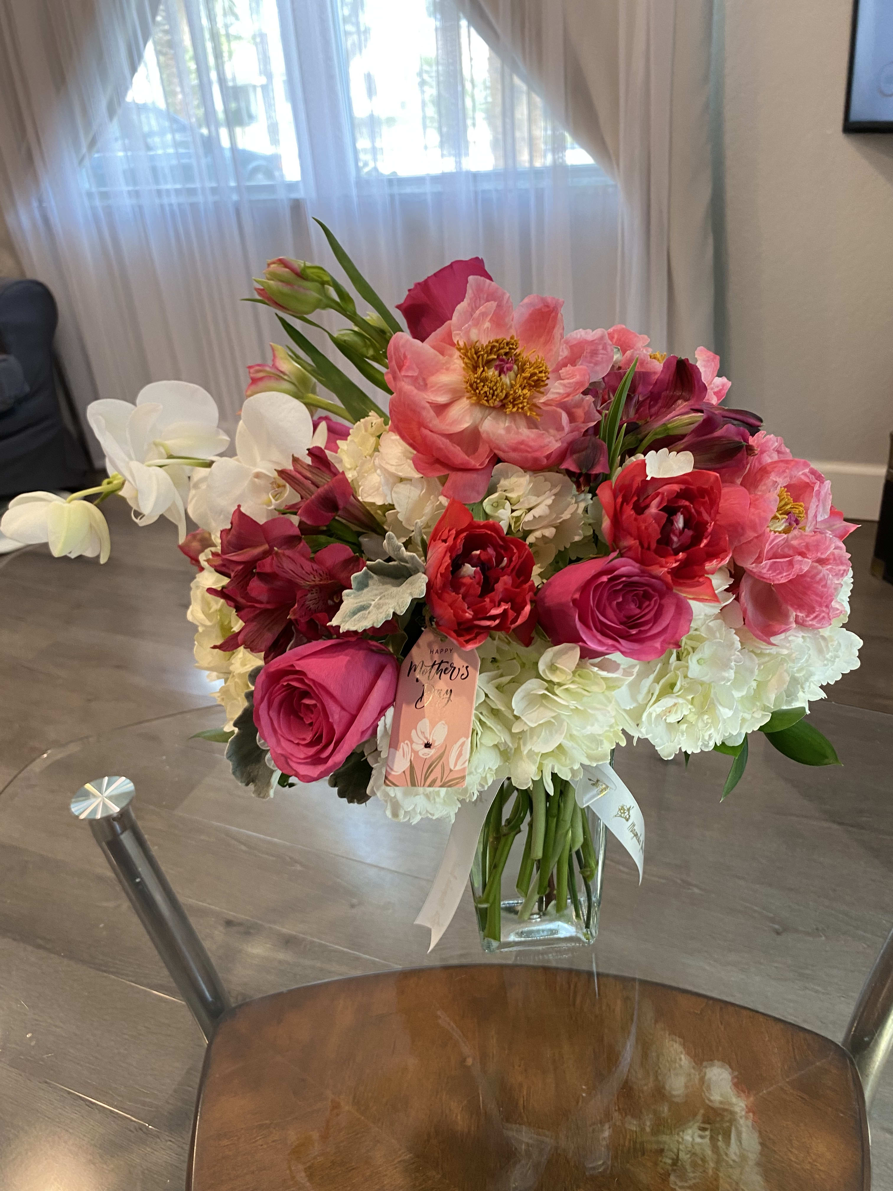 Pink and white mixed bouquet in a glass vase with a Mother's Day tag