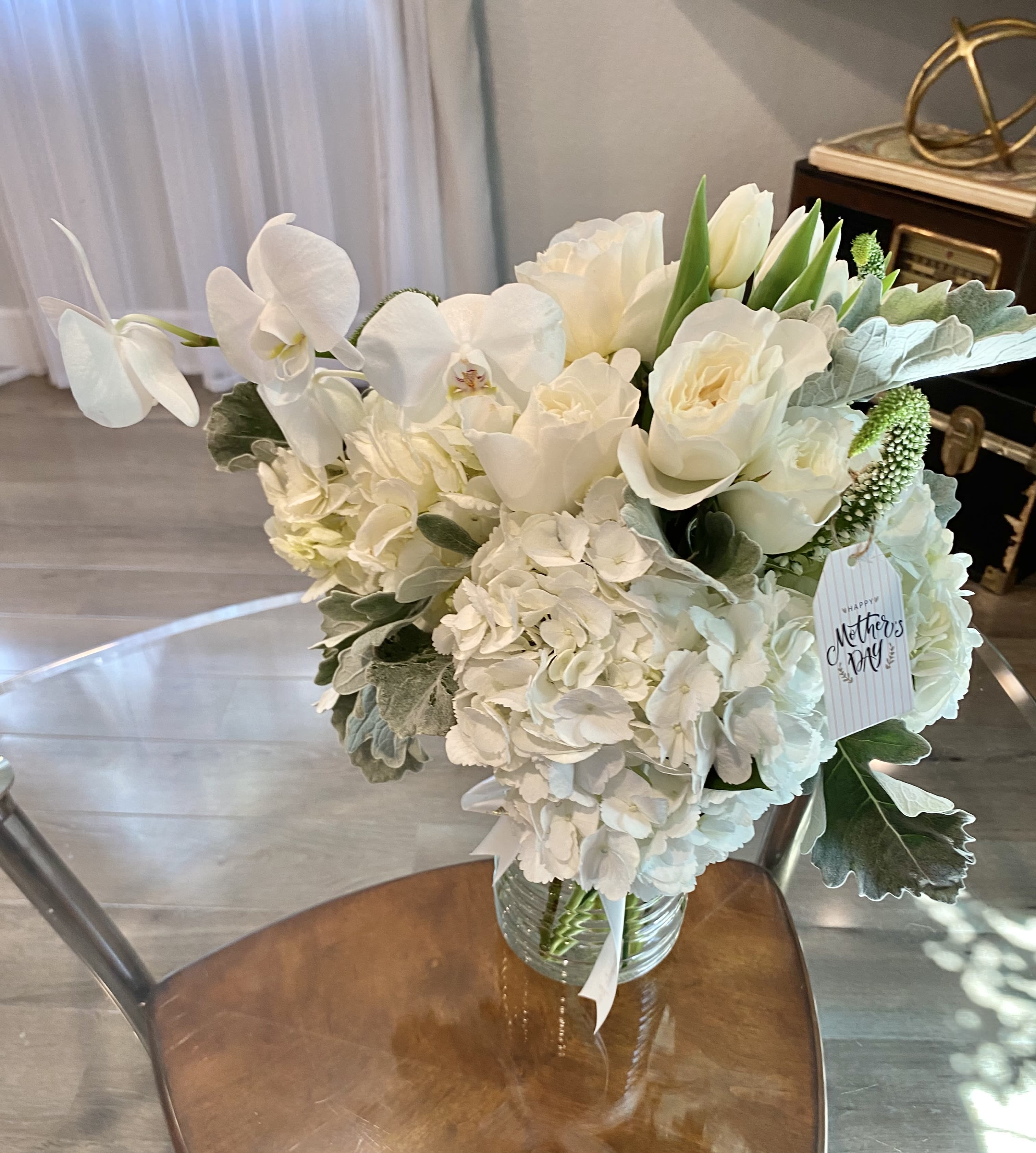 White floral bouquet in a glass vase with a Mother's Day tag