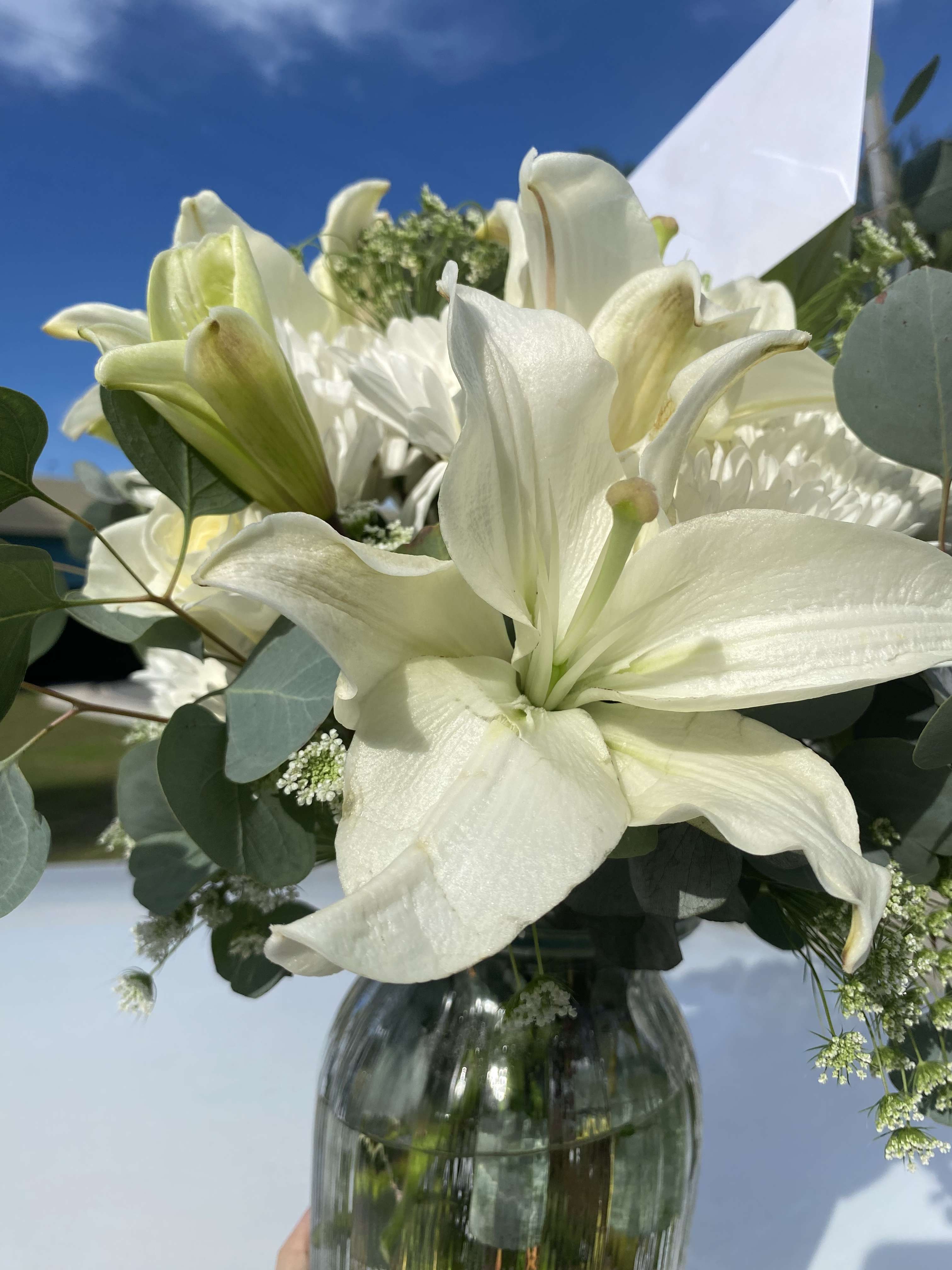 White lilies in a glass vase with eucalyptus