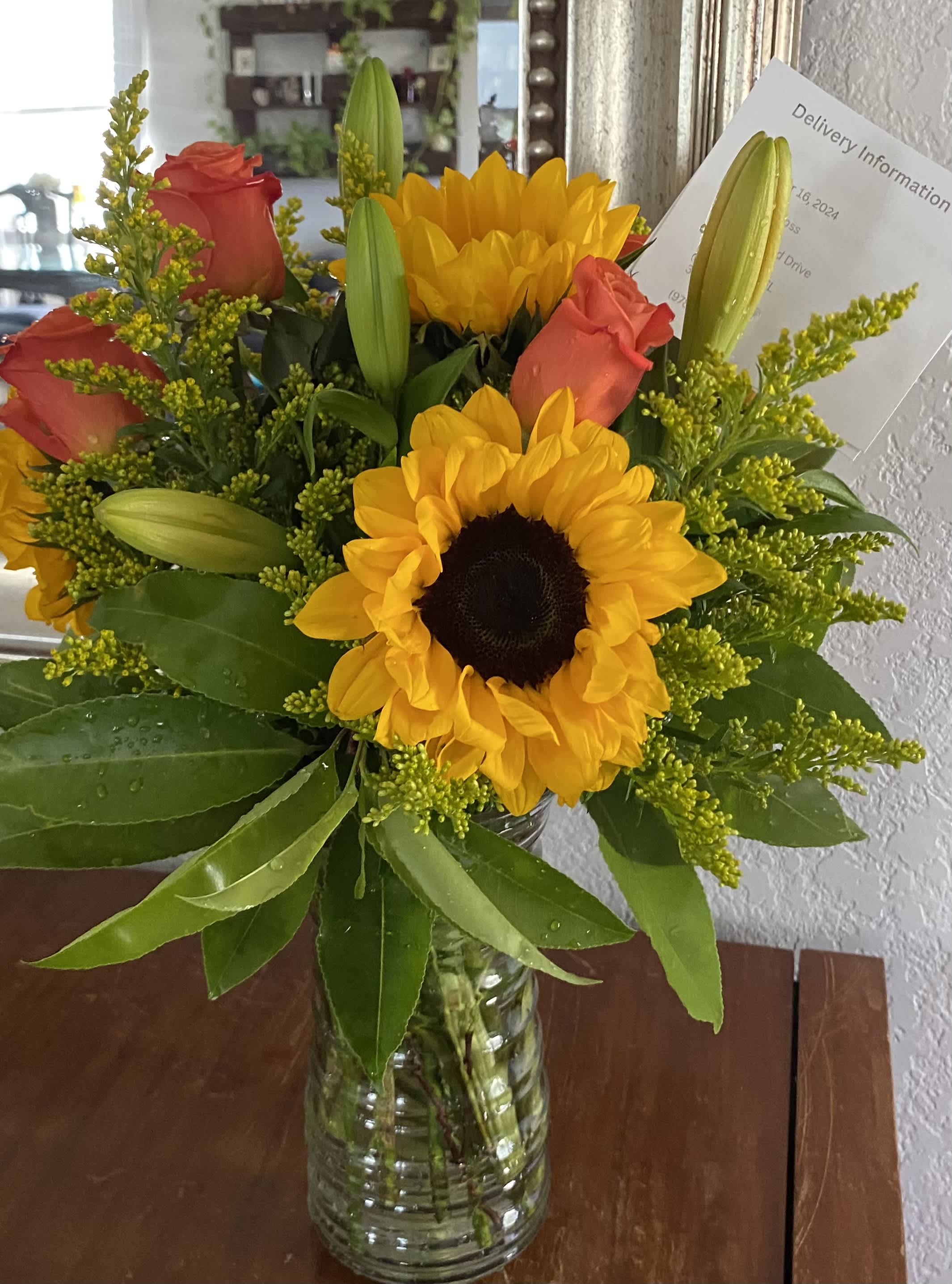 Sunflowers and red roses in a clear glass vase