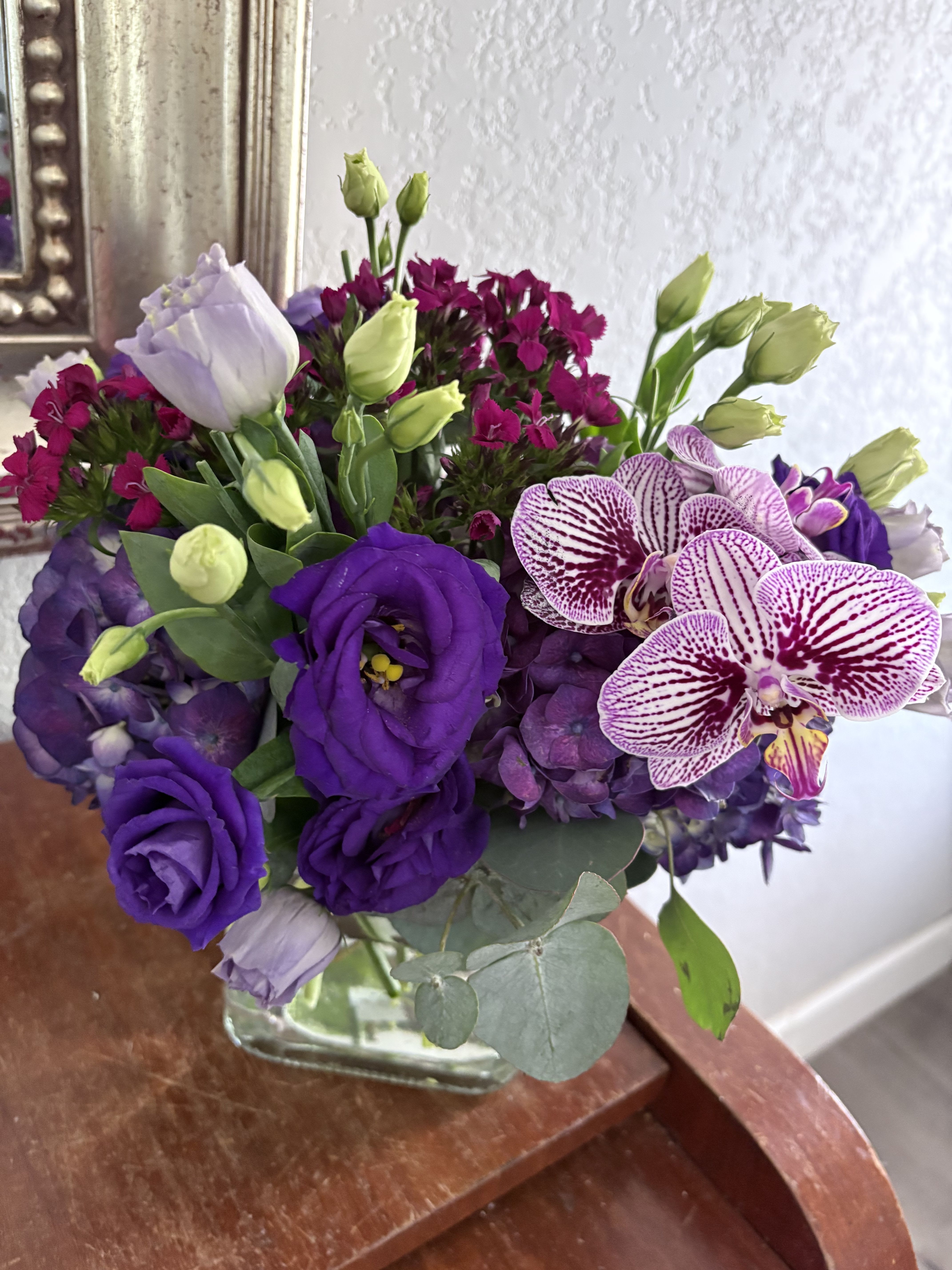 Purple bouquet with orchids, lisianthus, hydrangea, and a glass vase