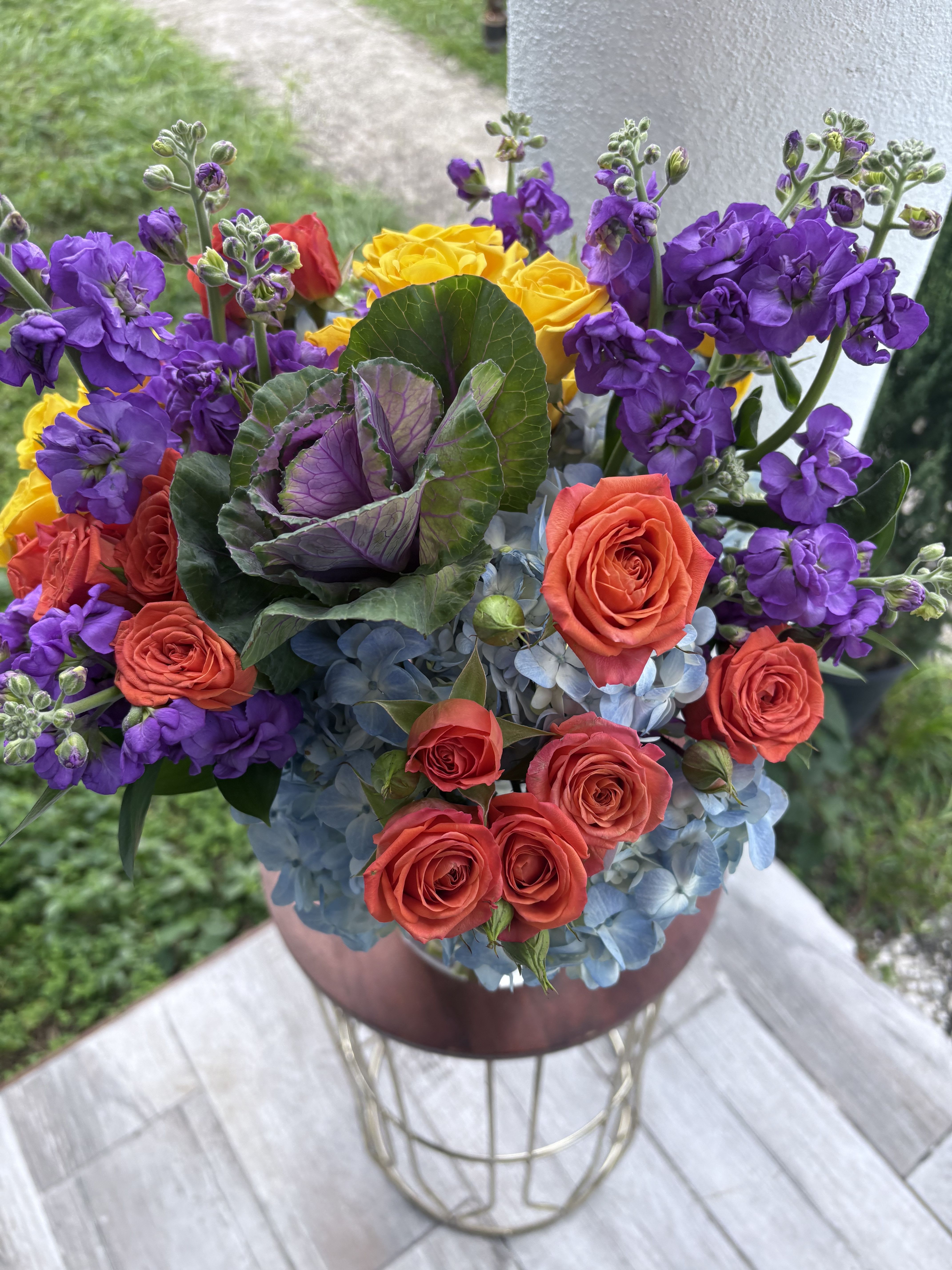 Colorful bouquet of roses, purple stock, and blue hydrangeas in a vase