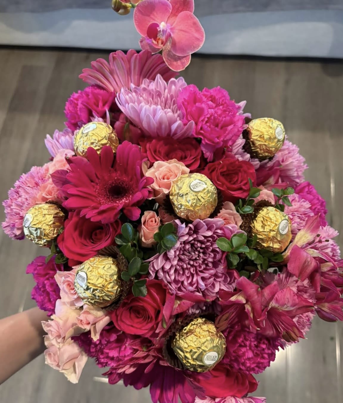 Pink bouquet with roses, chrysanthemums, orchids, and gold-wrapped chocolates