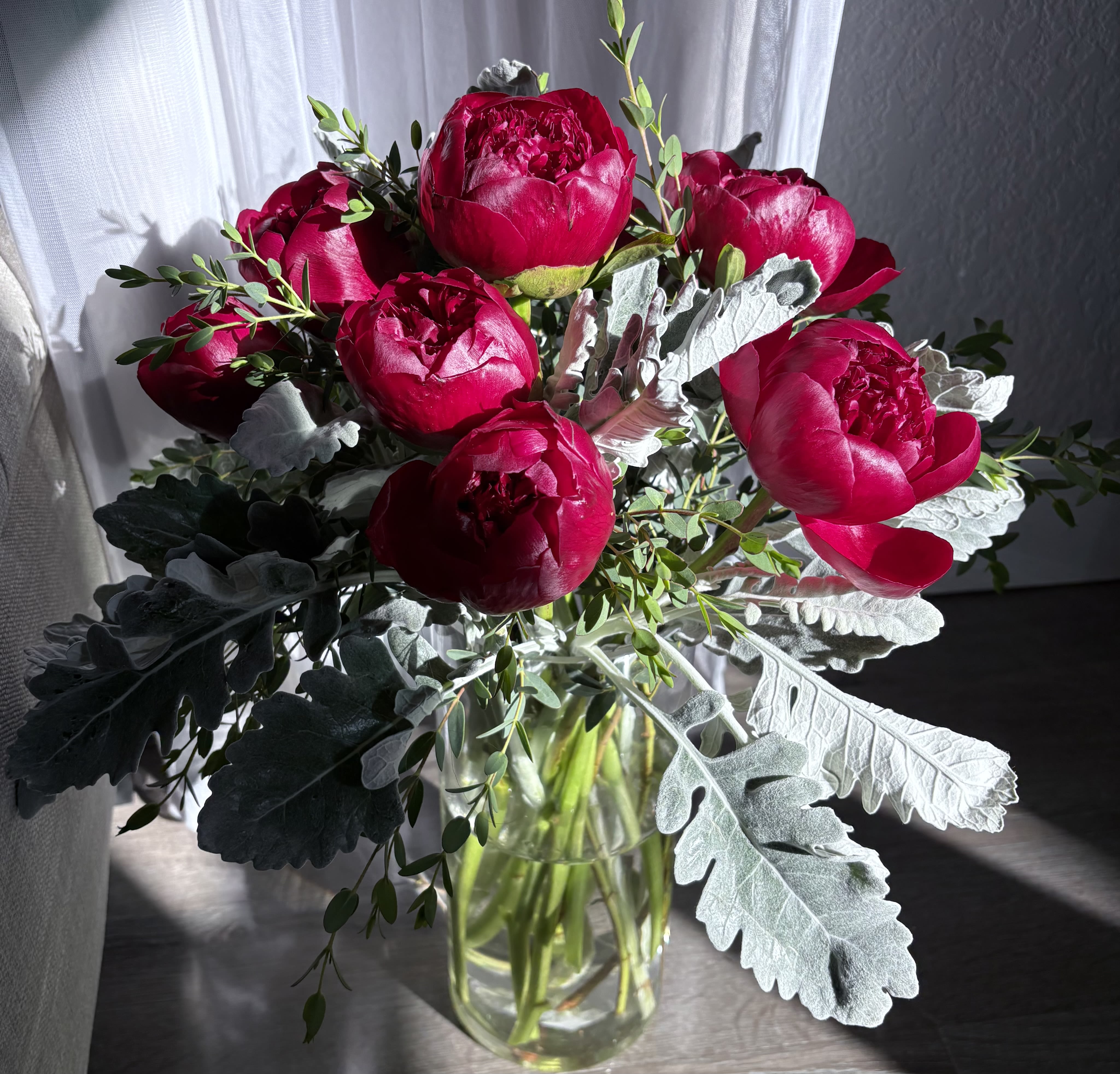 Bouquet of deep pink peonies in a clear glass vase