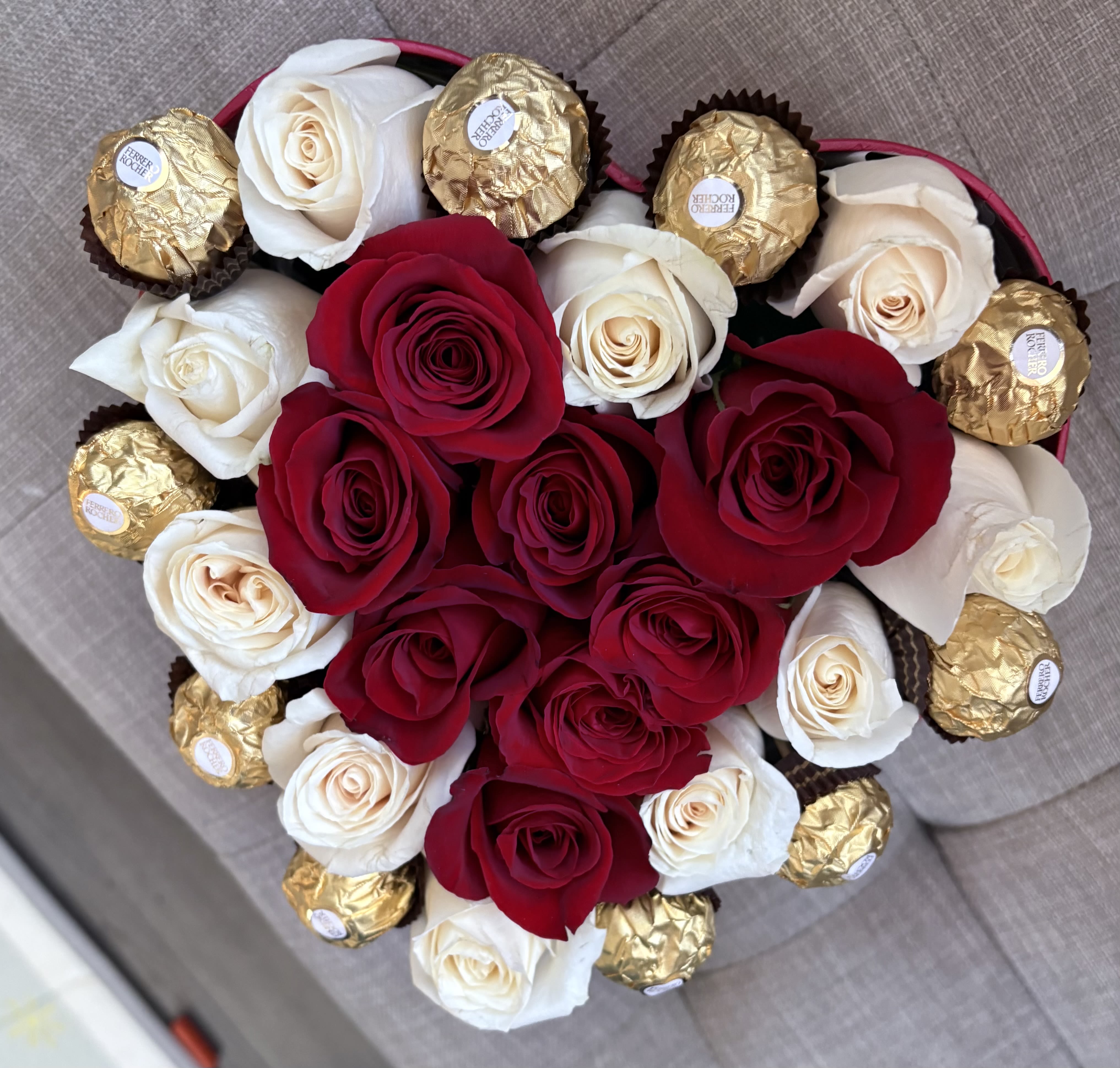 Heart-shaped bouquet of red and white roses with gold-wrapped chocolates