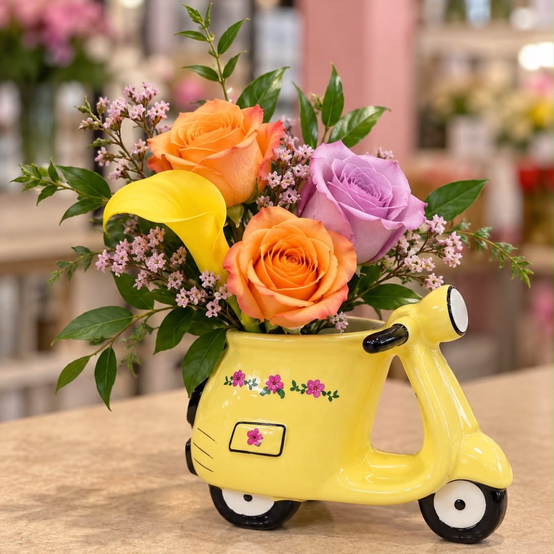 Bouquet of roses and calla lilies in a yellow scooter-shaped vase