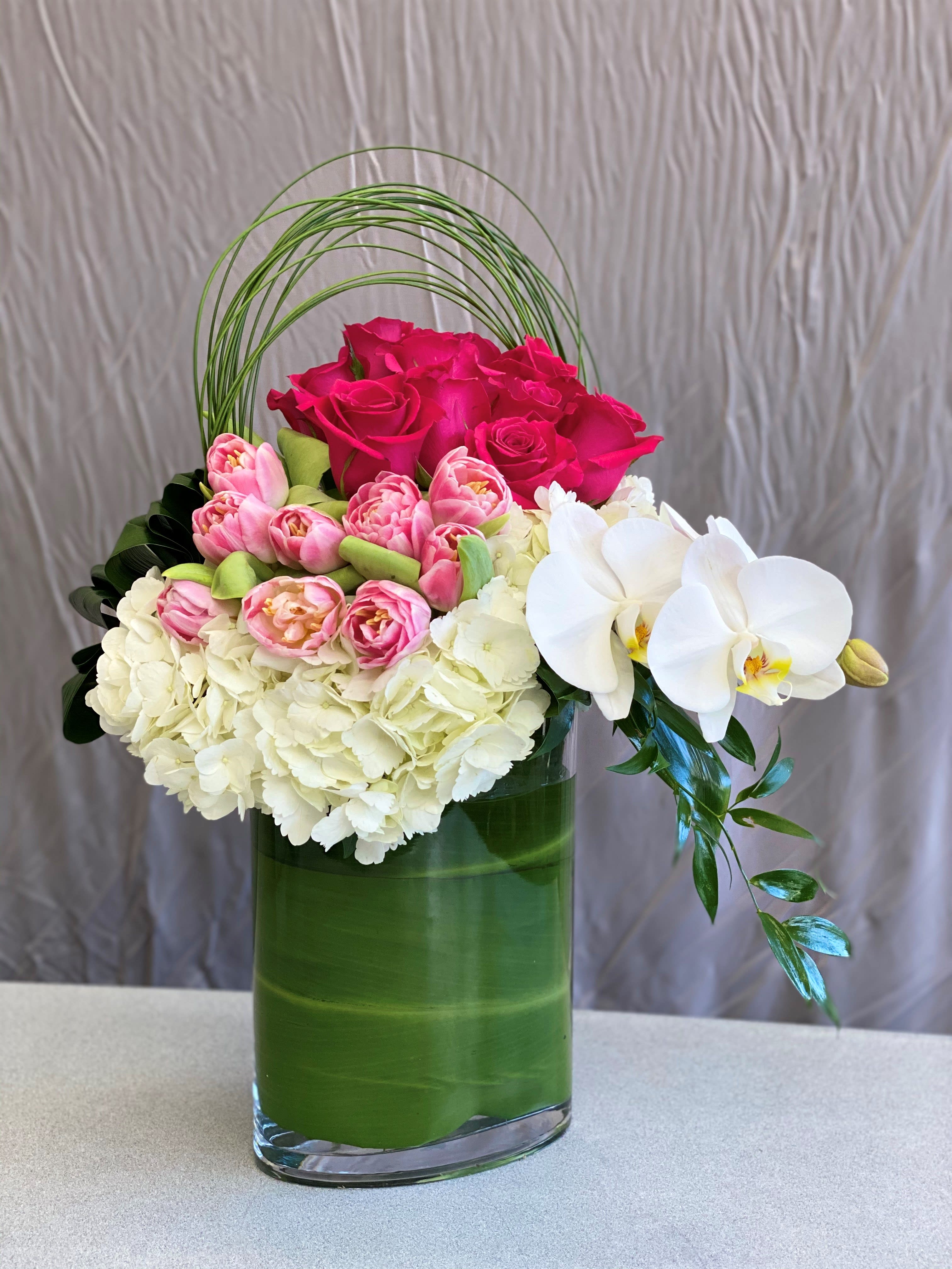 Pink roses, white hydrangeas, and white orchids in a green vase
