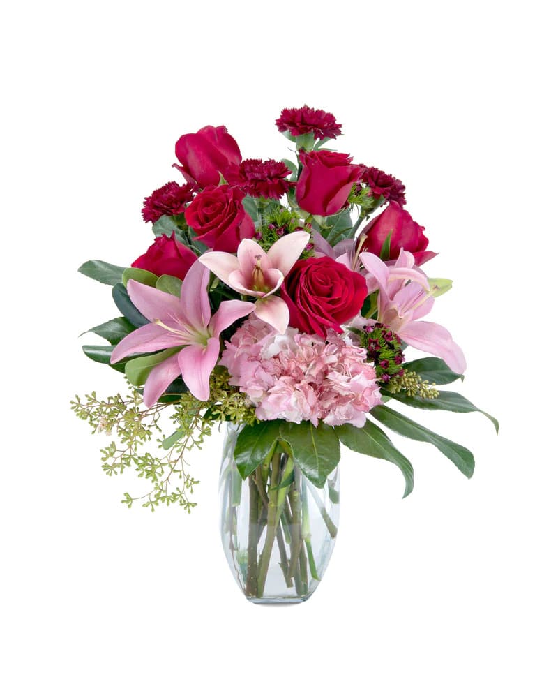 Pink lilies and red roses arranged in a clear glass vase