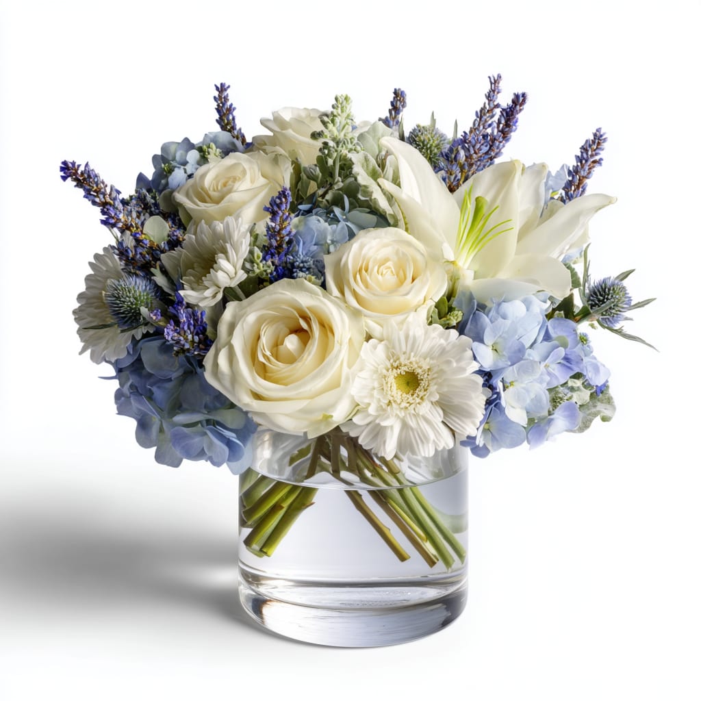 White roses and lilies with blue hydrangeas in a glass vase