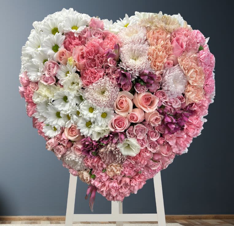 Heart-shaped floral arrangement of pink and white flowers on a stand