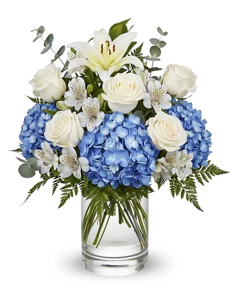 Blue hydrangeas and white roses in a clear glass vase