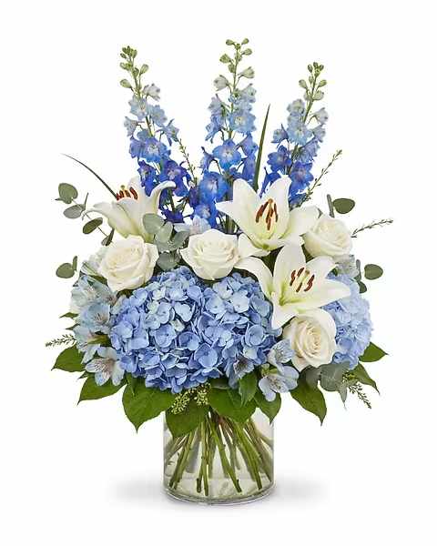 Blue hydrangeas, white lilies, and roses in a glass vase
